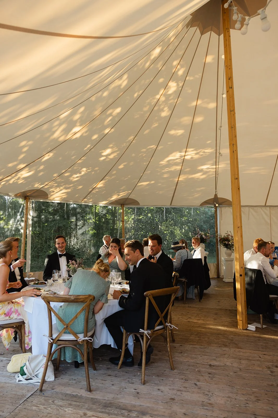 Gjestene fordelt rundt et dekket bord under en partytelt.