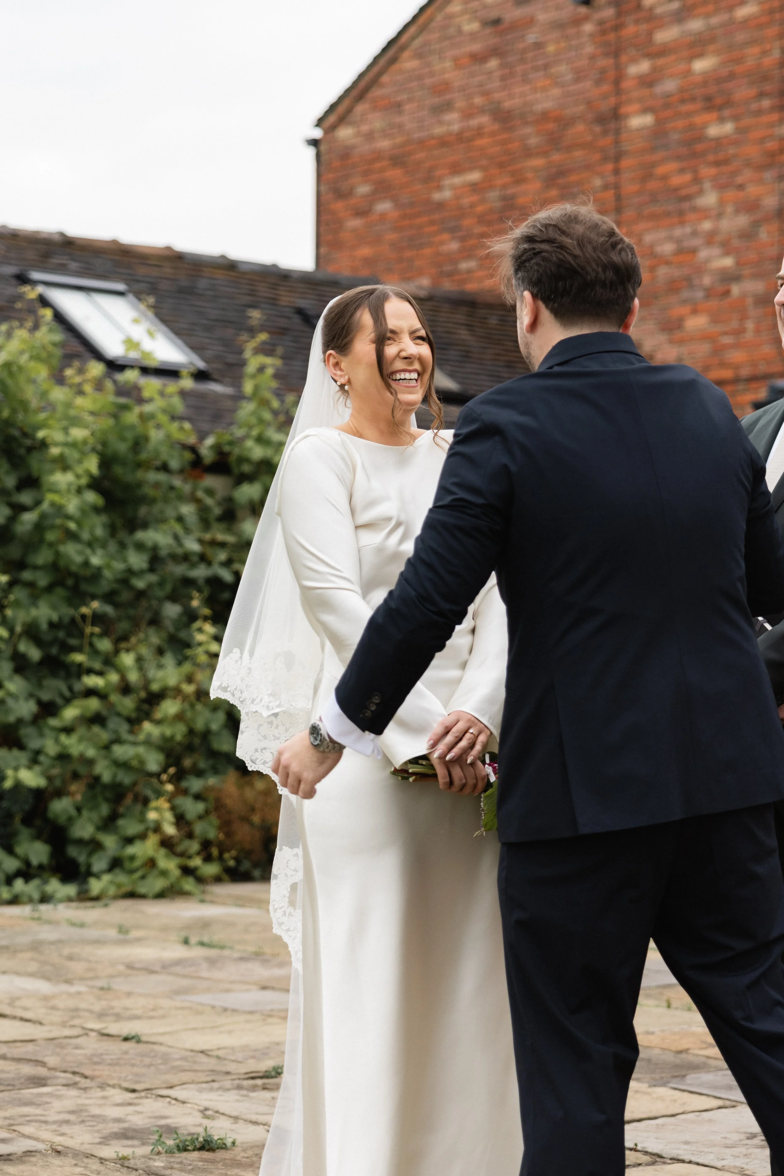 Et brudepar som ler og holder hender under vielsen utendørs.