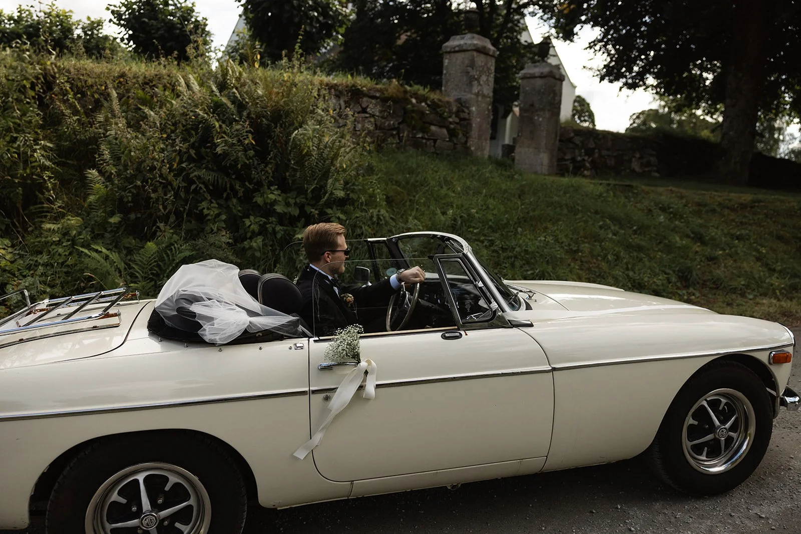 En mann og kvinne i bil, kledd i brudeklær, på vei til bryllup
