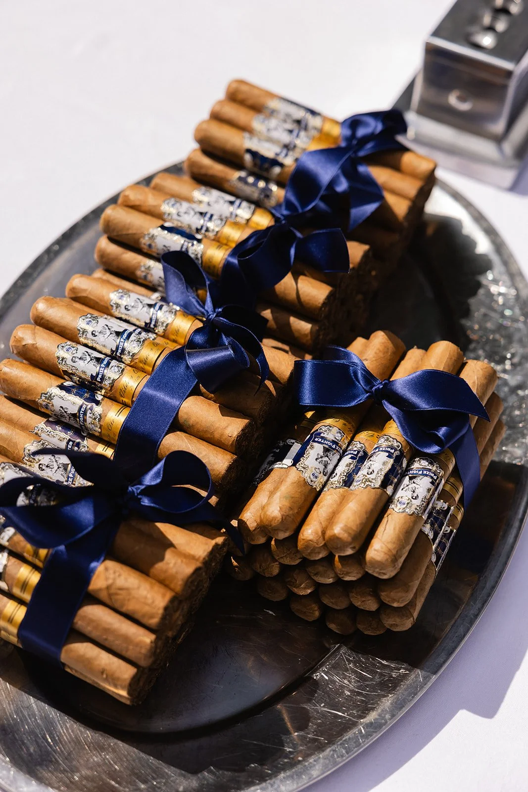 Noen store kuber av sigarilloer bundet med mørkeblå satinbånd, plassert på et sølvfat.