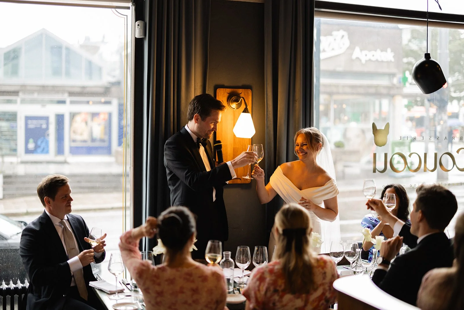 Et bryllupsmiddag med en brud og brudgom som skåler for gjestene i en restaurant eller kafé.