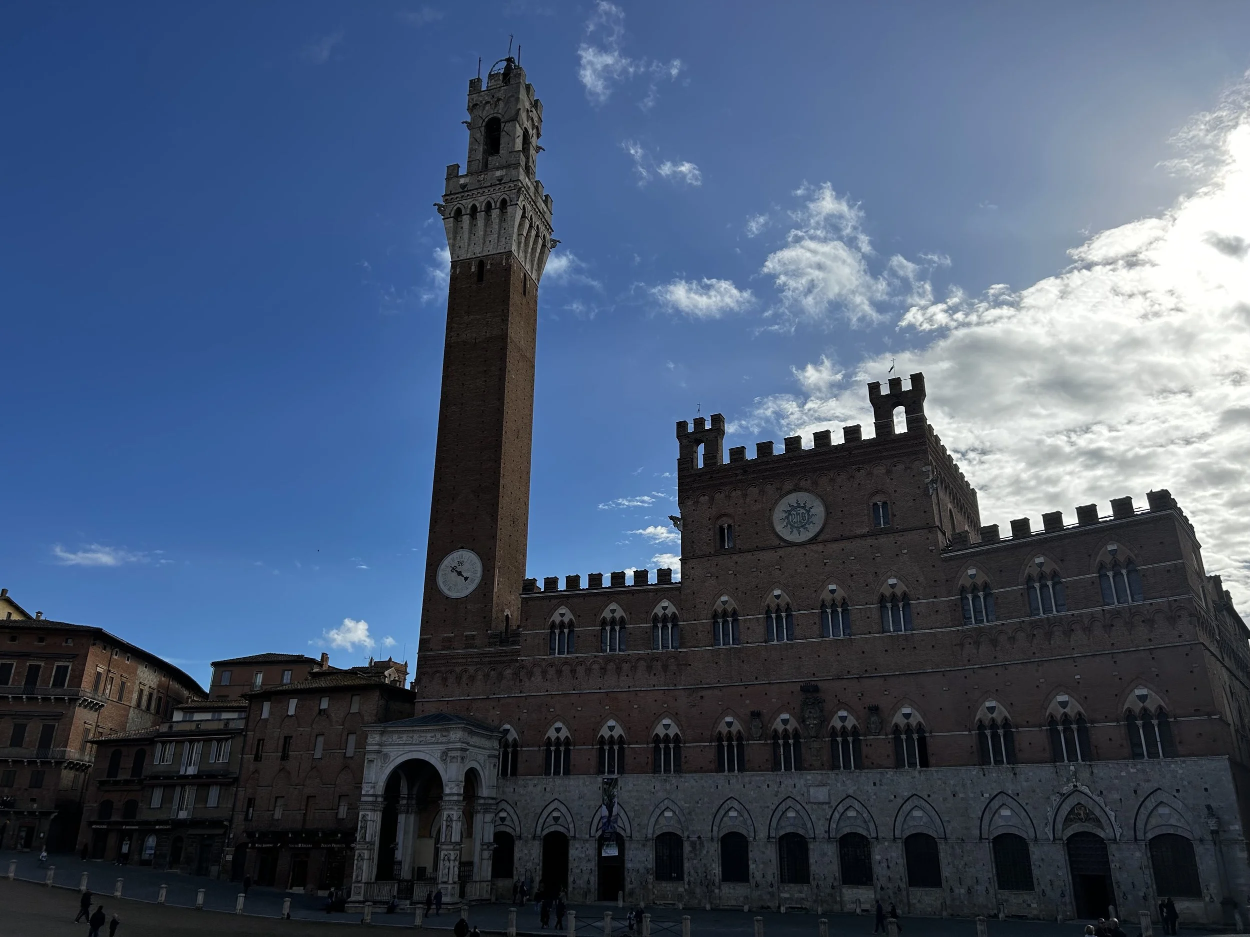 View of the Palazzo Vecchio with its tall clock tower in Florence, Italy, during the daytime with a partly cloudy sky.