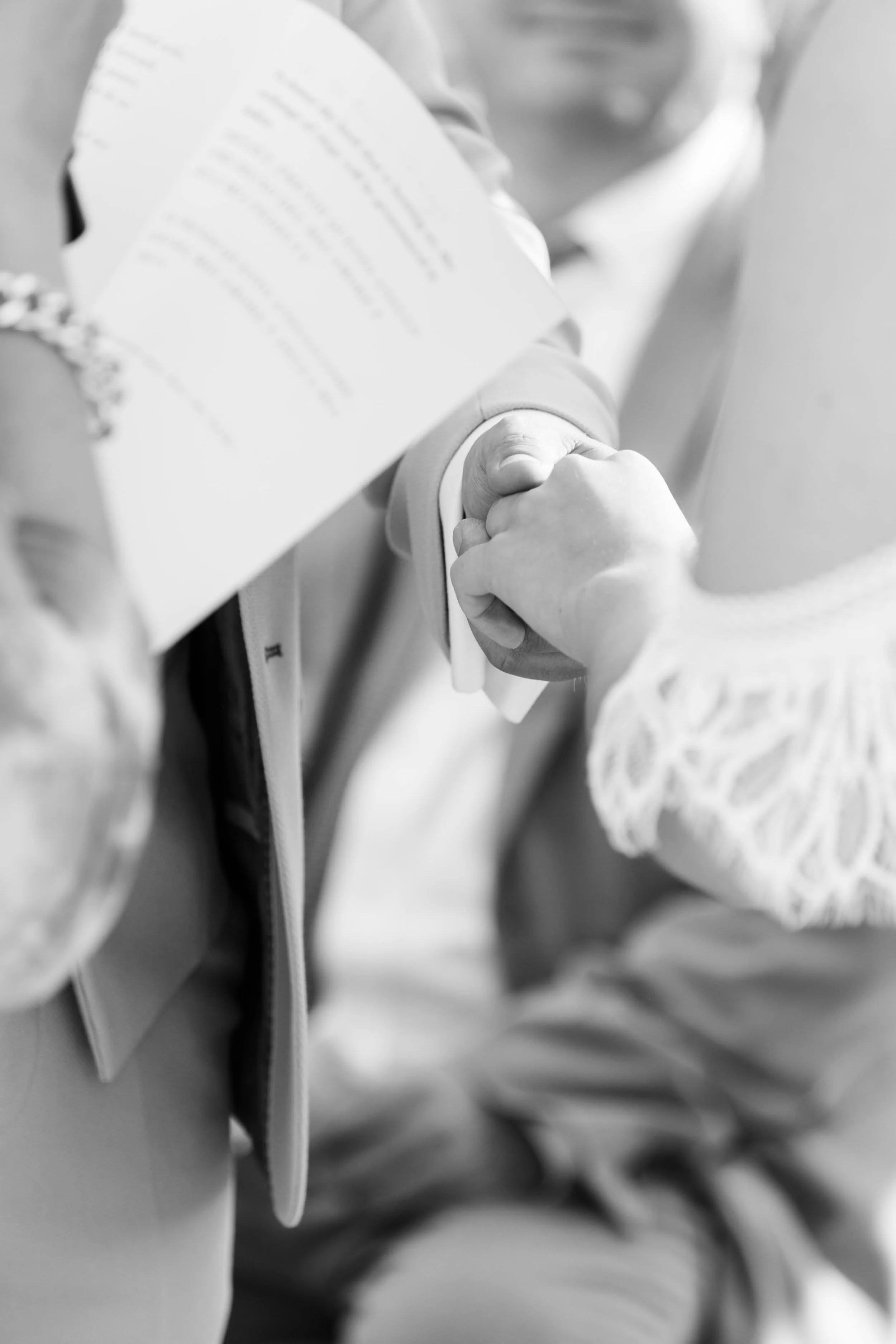 A close-up black and white photo of two people shaking hands, with one person holding a piece of paper or certificate.