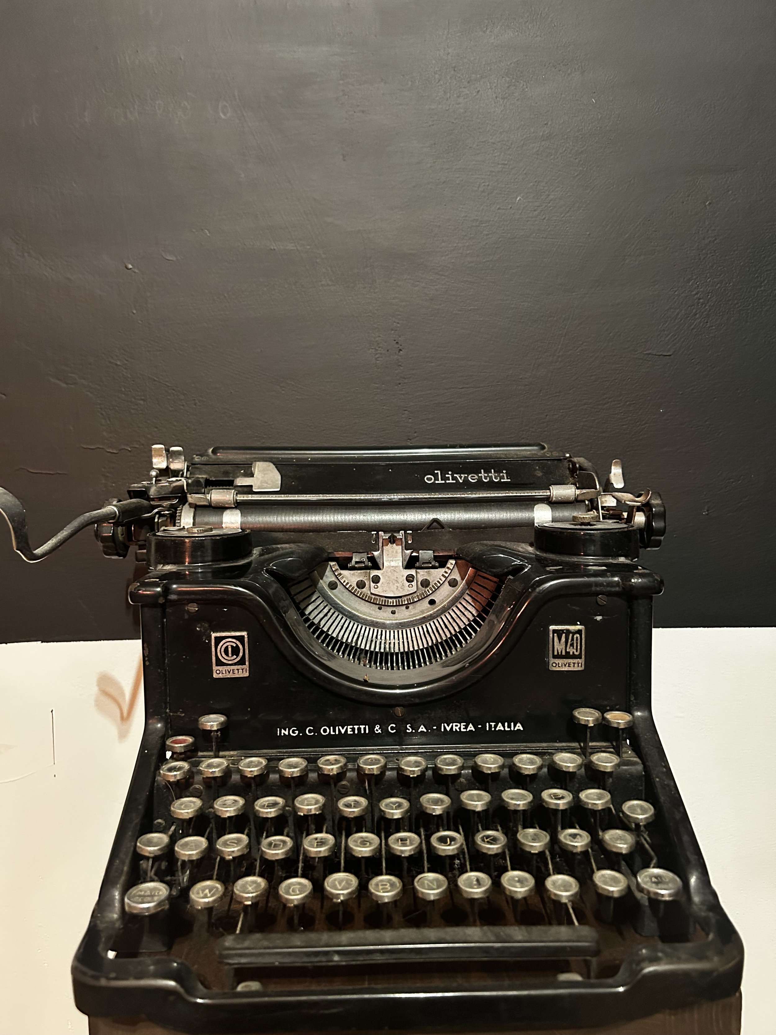 Vintage black Olivetti typewriter on a white surface.