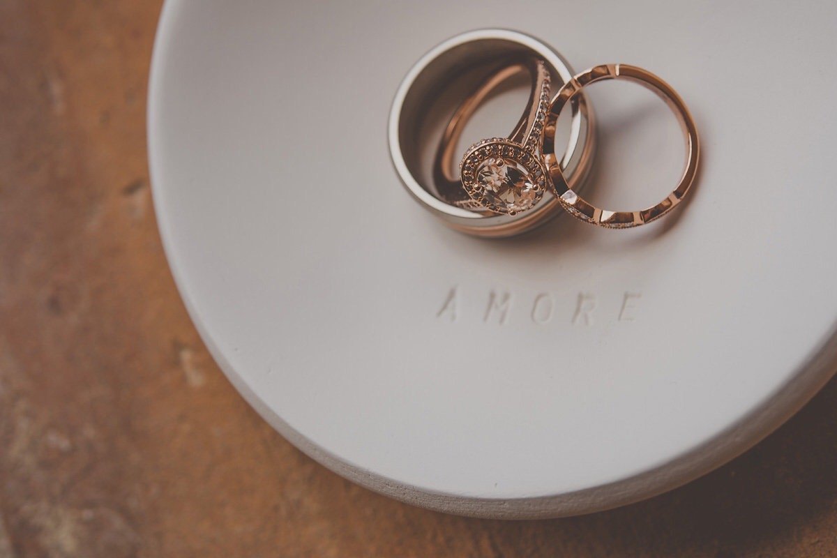 Three rings in a container on a white dish with the words 'A MORE' embossed on it, set on a textured brown surface.
