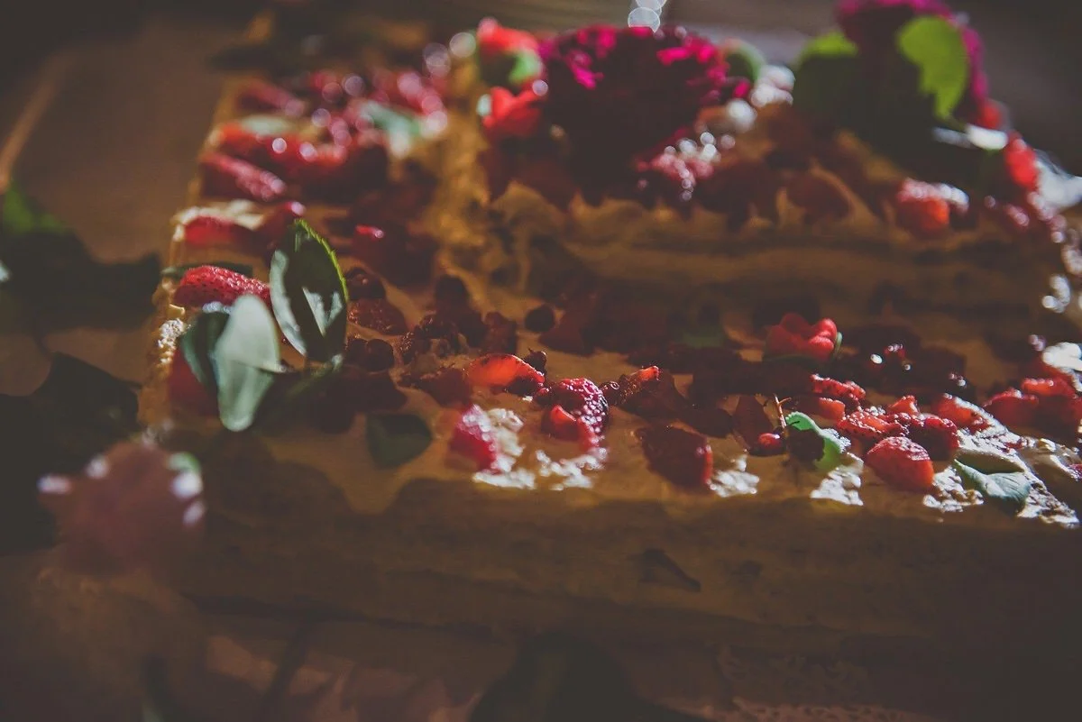 A close-up of a layered cake decorated with red berries and green leaves on top.