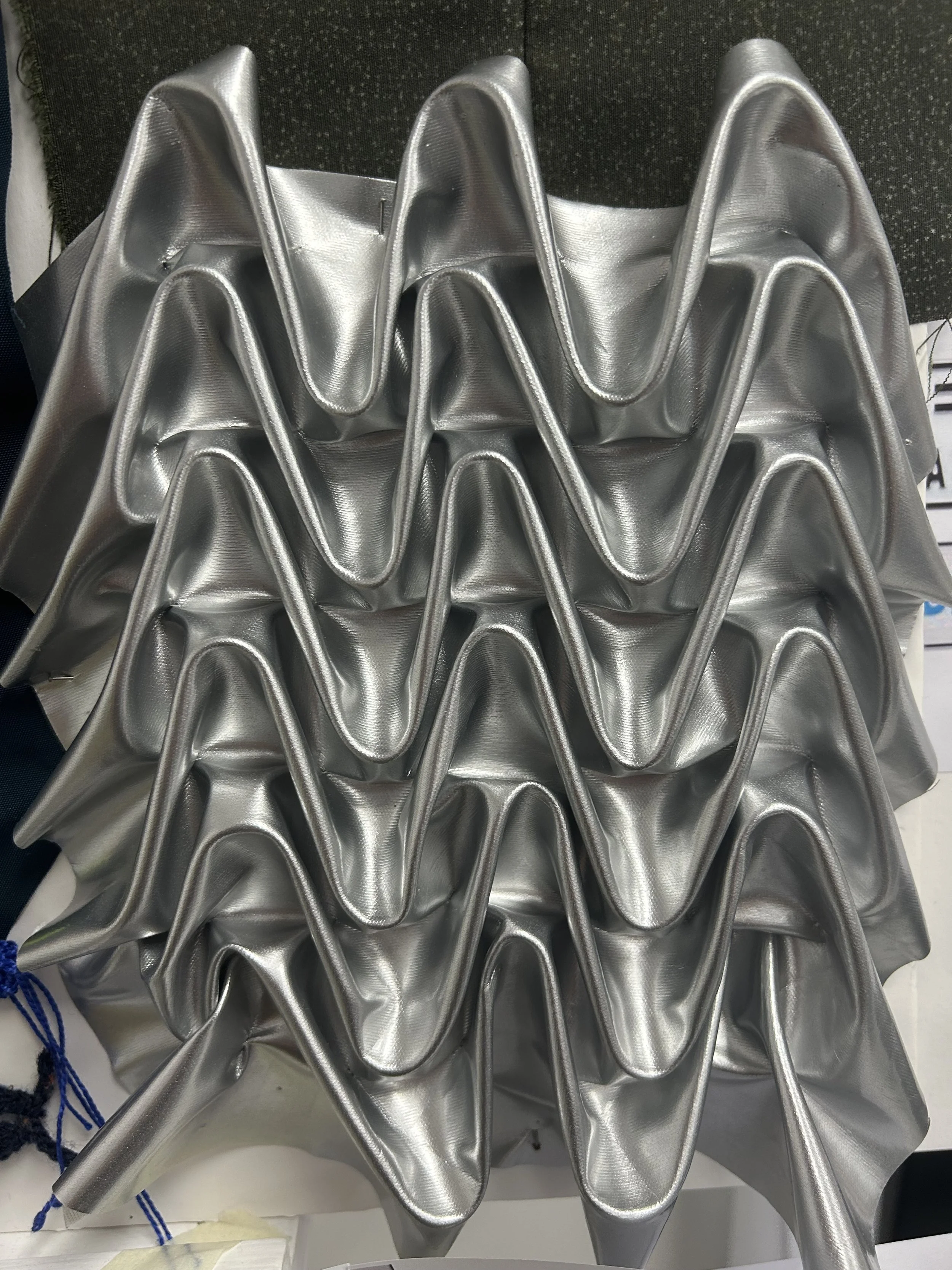 Multiple metallic silver funnel-like objects stacked together, shiny and reflective.