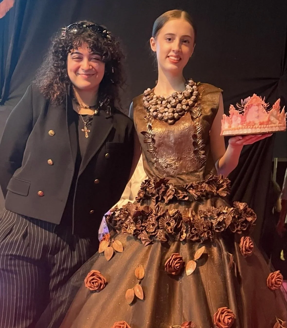 Tugali Jarrouj standing beside a model wearing a baroque-inspired chocolate dress with a white chocolate crown backstage at Salon du Chocolat Dubai 2024.
