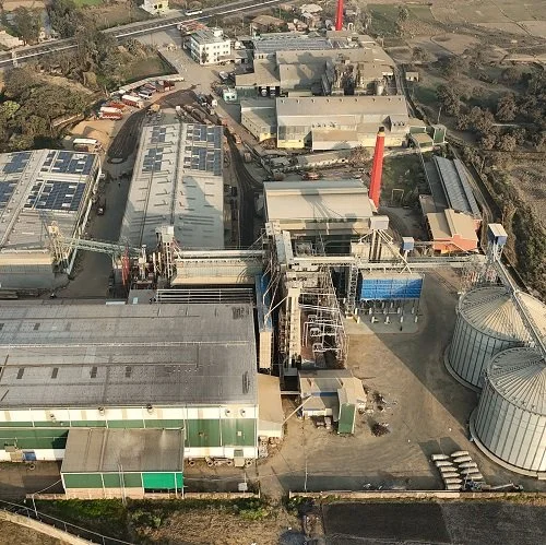 Aerial view of an industrial complex with multiple large buildings, silos, and chimneys.
