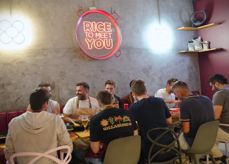 Comensales en el comedor del restaurante Rice to Meet You, junto al neón de la marca, en el Raval de Barcelona
