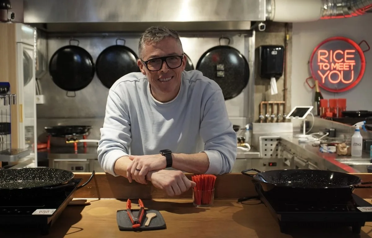 Leo Pavanetto in the Rice to Meet You kitchen in El Raval, Barcelona, with the paella pans hanging behind him