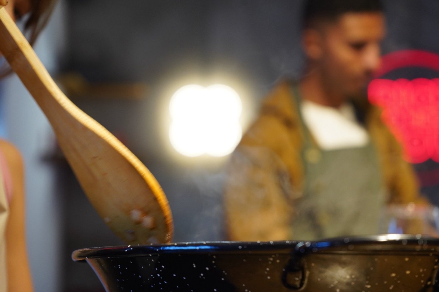 Wooden spoon stirring the freshly cooked paella with steam rising, paella cooking class in Barcelona