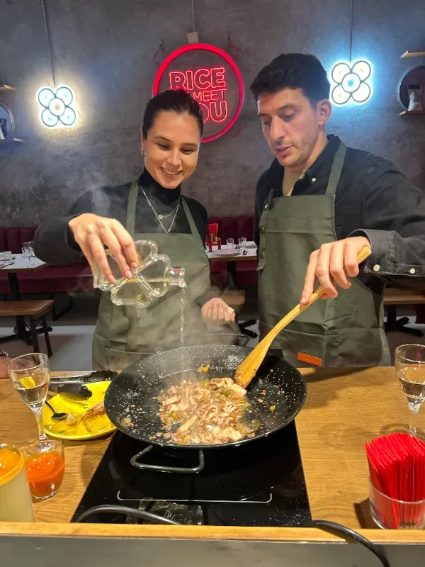 Pareja cocinando paella juntos en el taller de Rice To Meet You en Barcelona