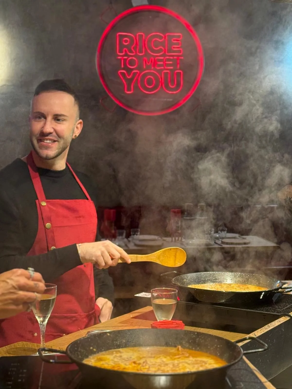 Chef del taller cocinando una paella con humo saliendo de la sartén en El Raval