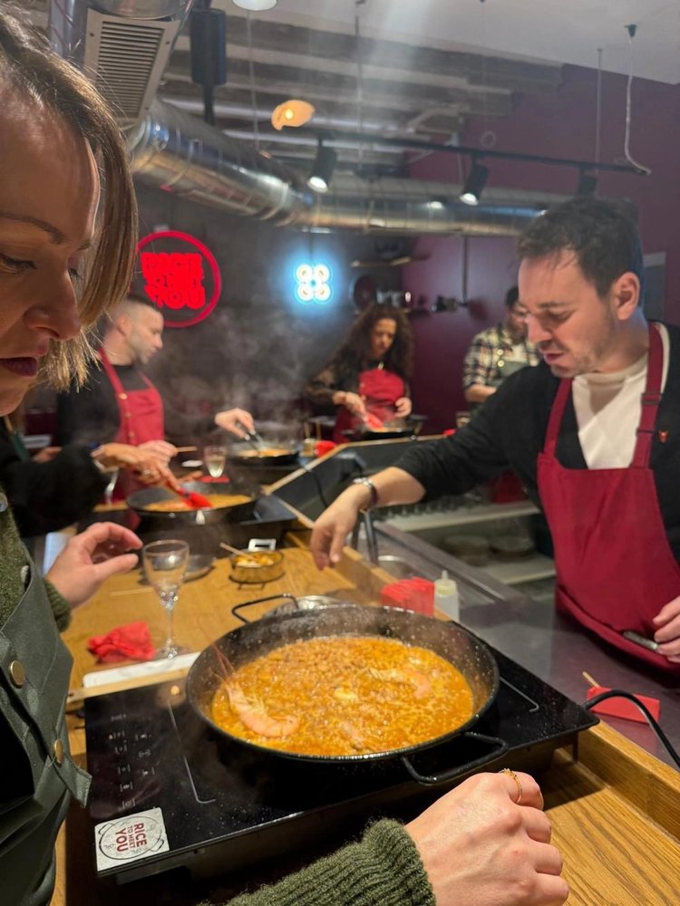 Grupo cocinando sus paellas alrededor de la barra en un team building en Barcelona