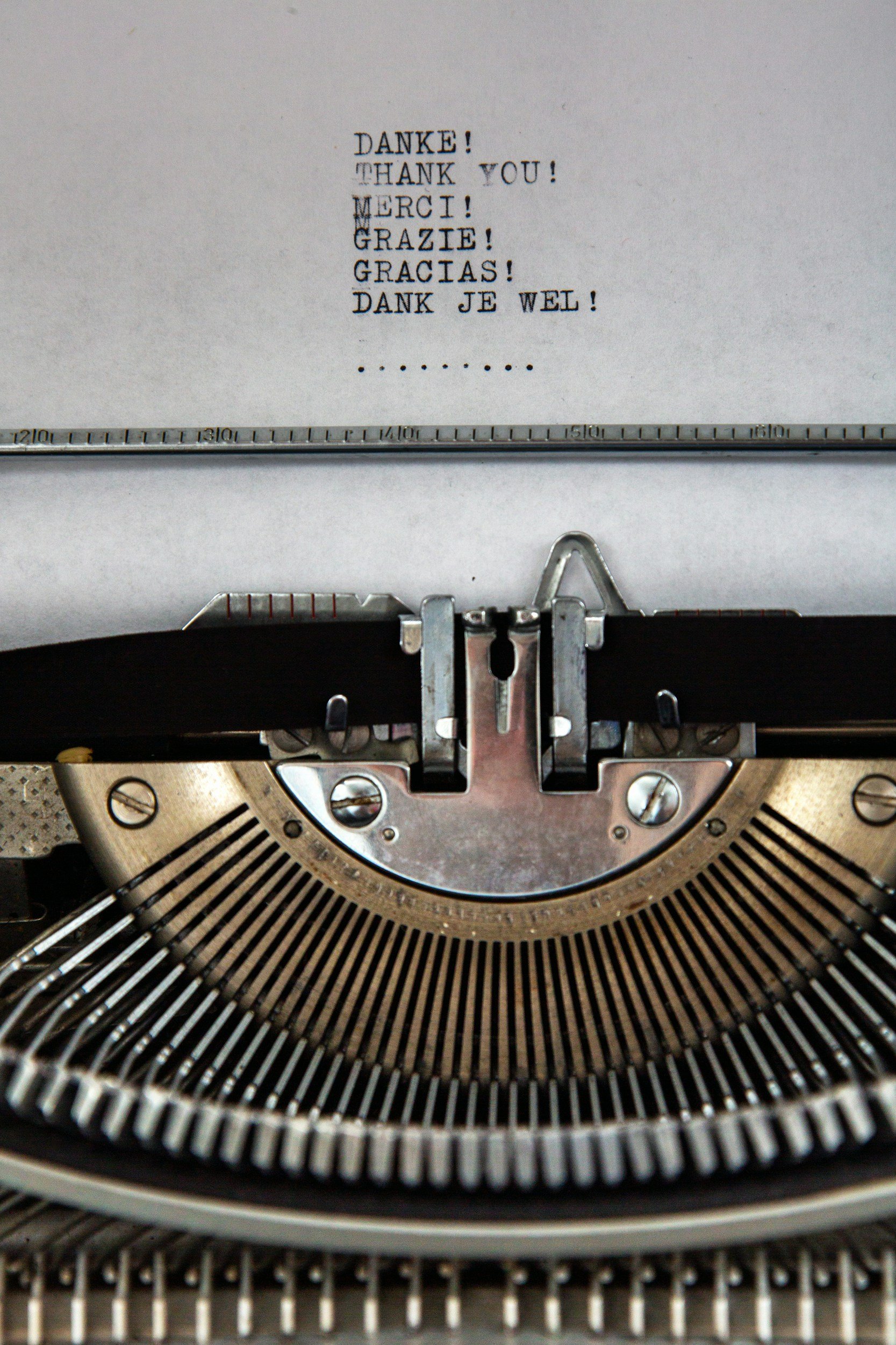 Close-up of a vintage typewriter with a sheet of paper showing the word 'Thanks!' in multiple languages.