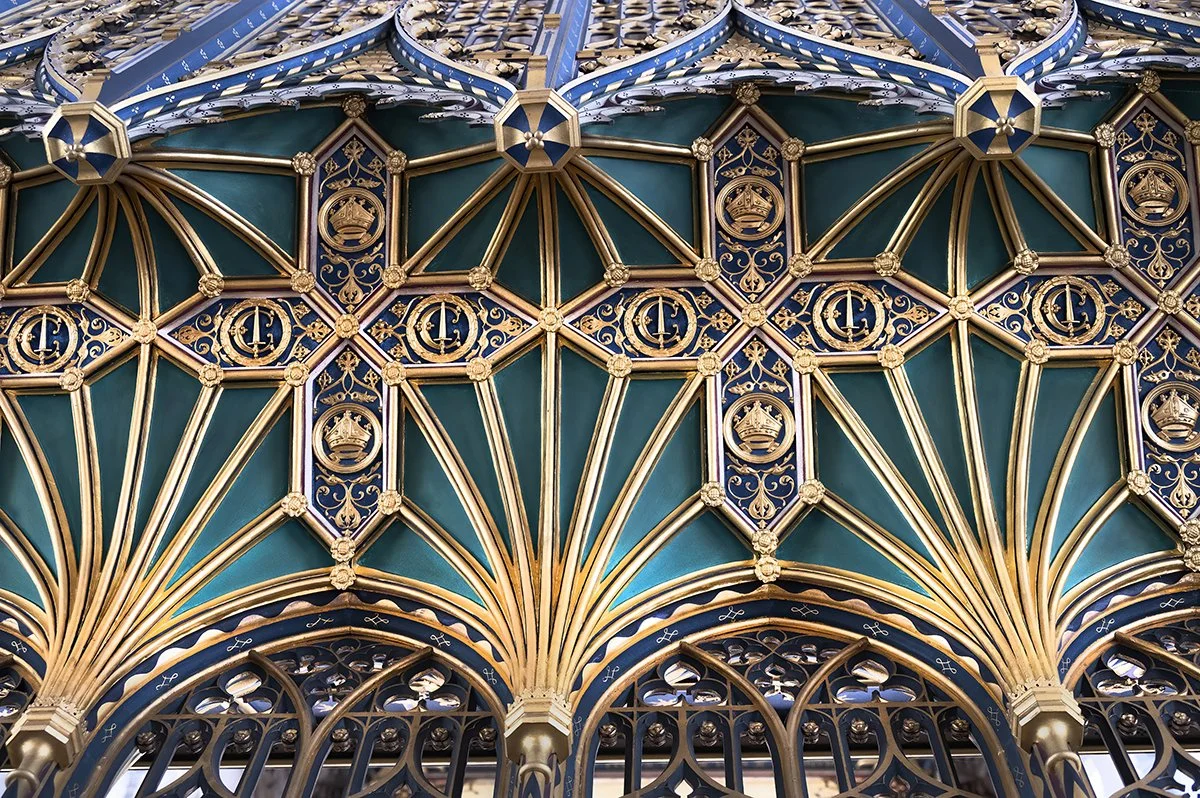 Decorative metalwork with ornate gold and blue design featuring crowns and scroll motifs.