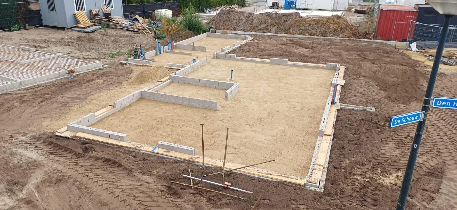 Verschillende funderingswerken en constructie van een gebouw in de bouw, met zand, stenen en bouwmateriaal op een bouwplaats.