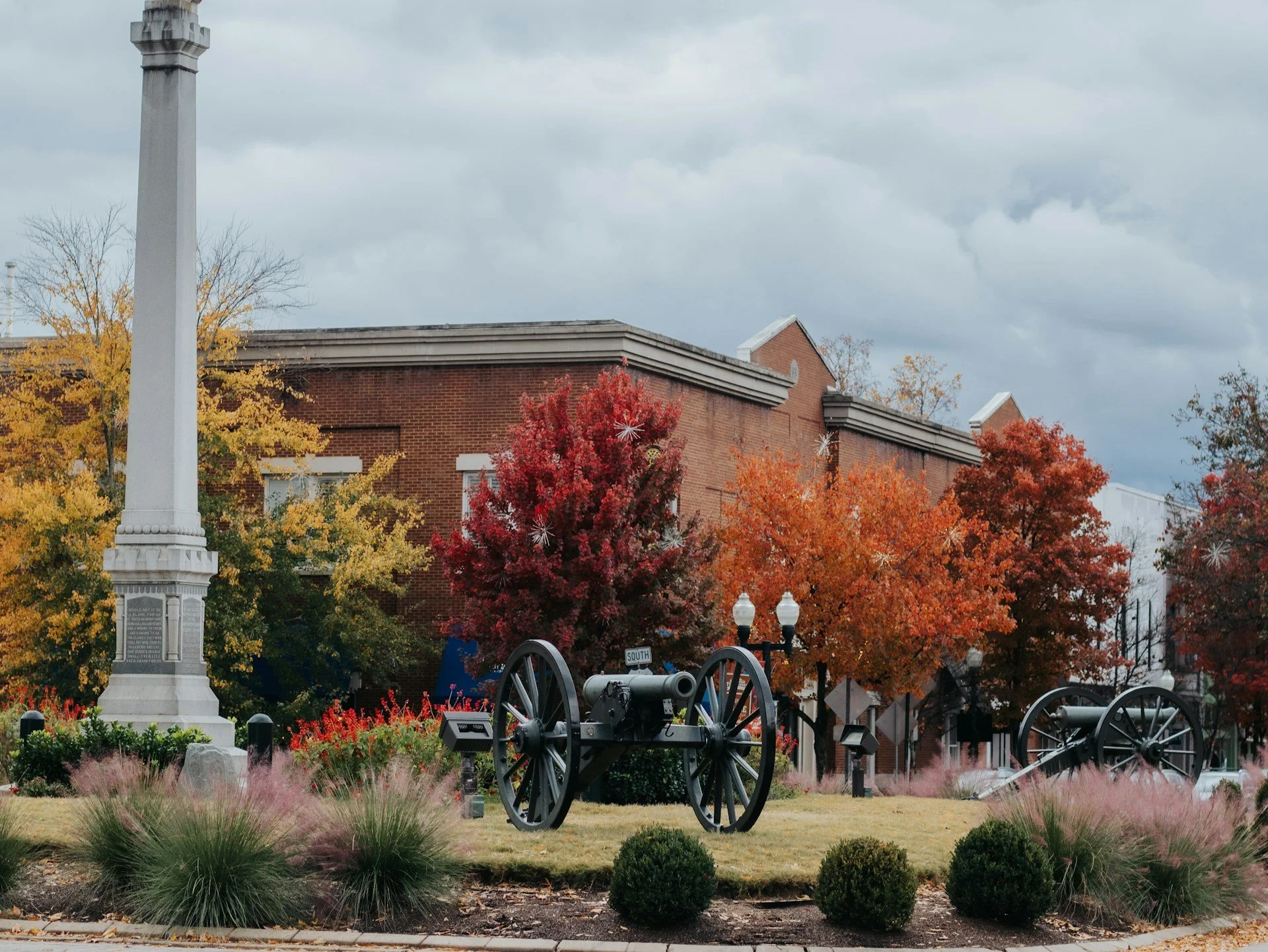 Picture of a canon and a cenotaph by some autumnal trees.