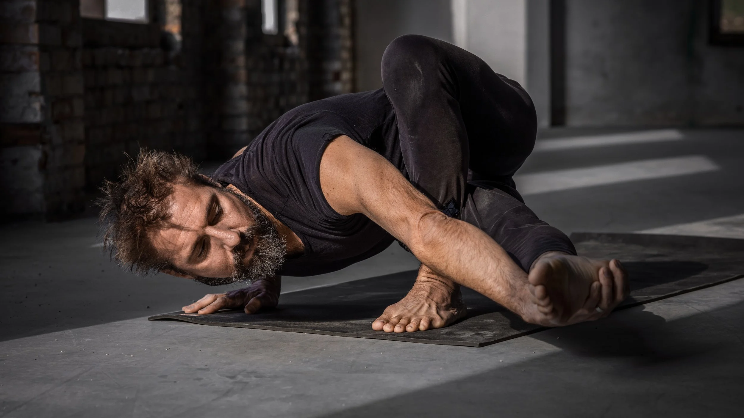 Man doing a yoga pose dressed in black