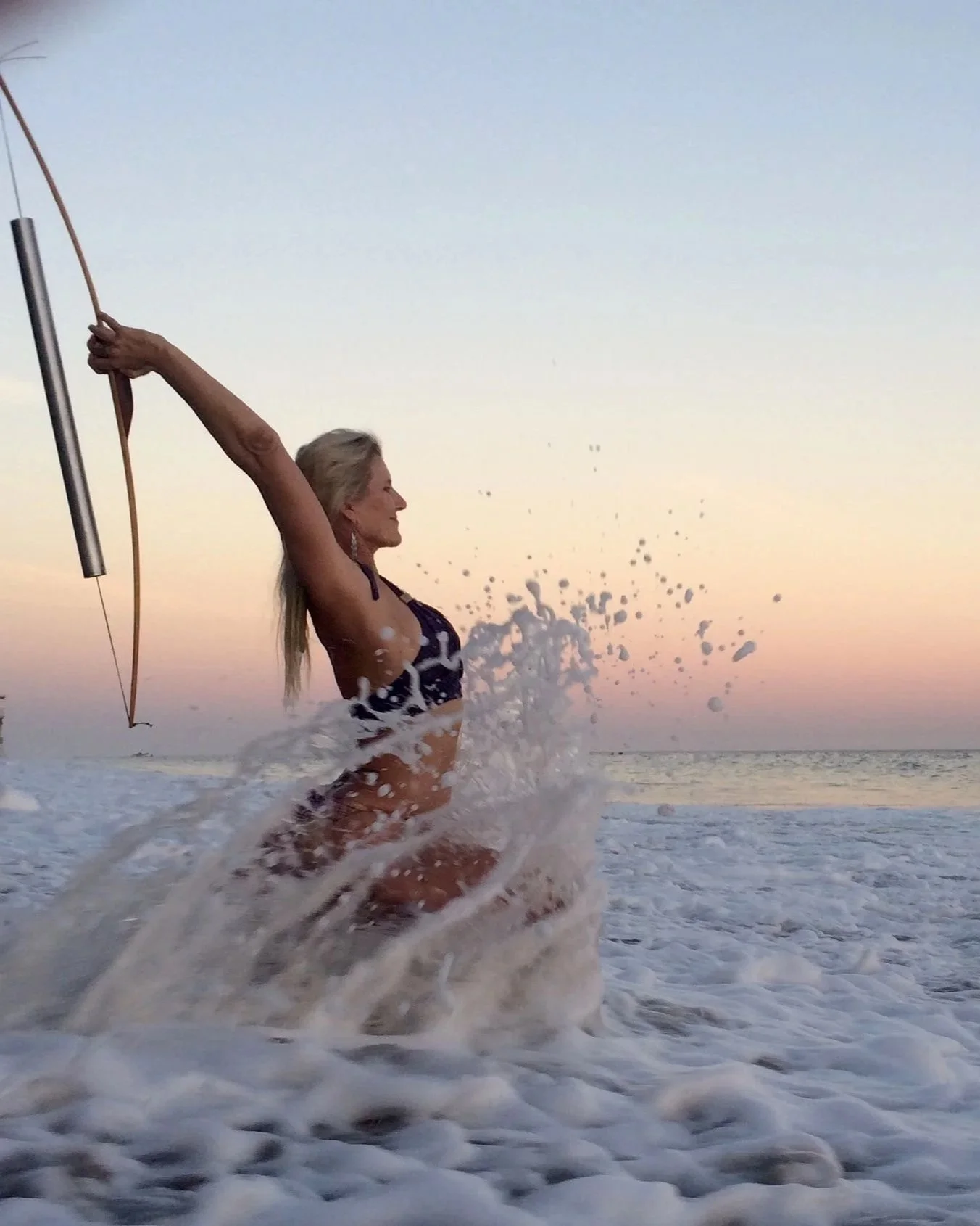Woman with a bow drawing at the beach during sunset.