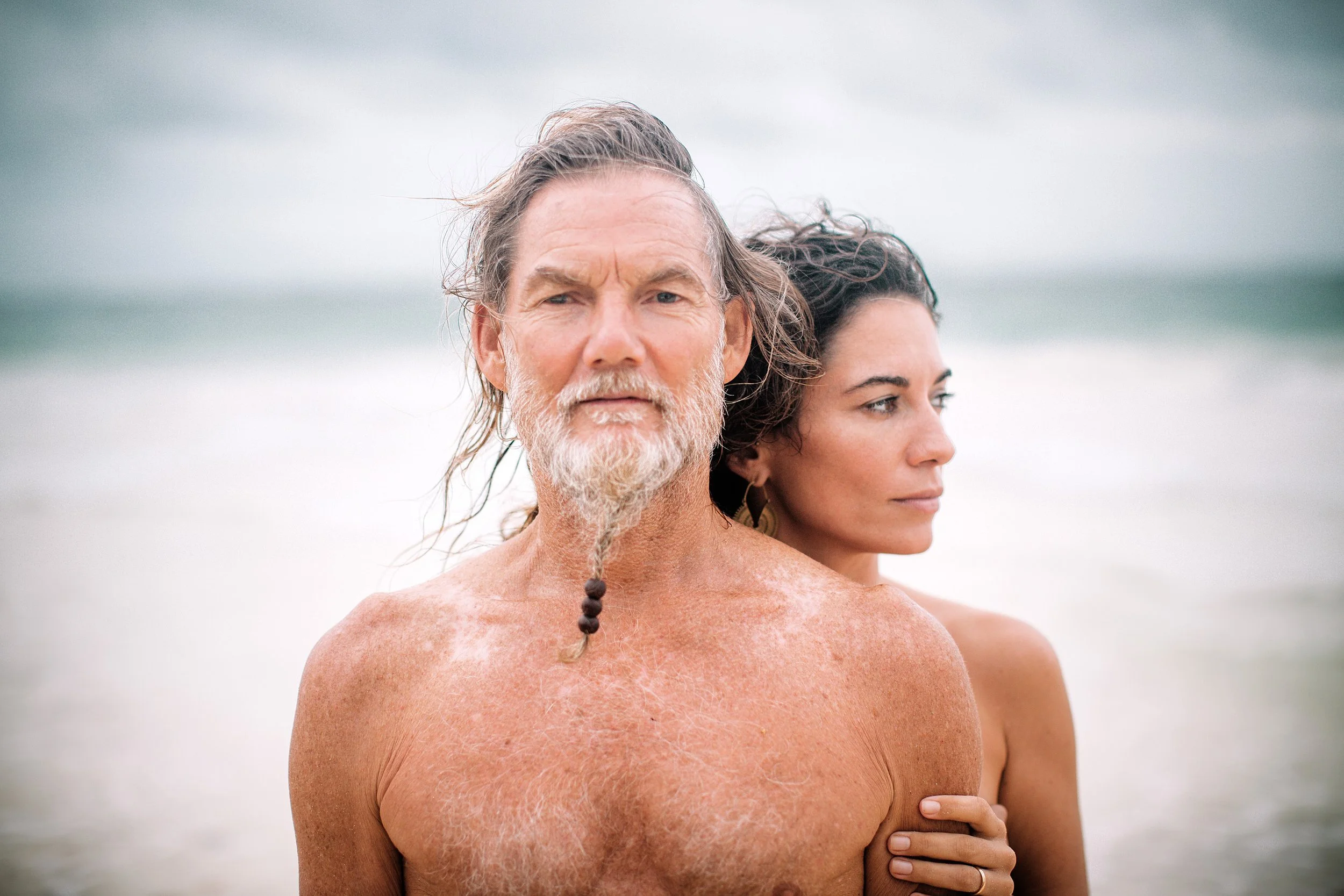 Older man with grey hair and a beard with a woman with dark hard standing behind him