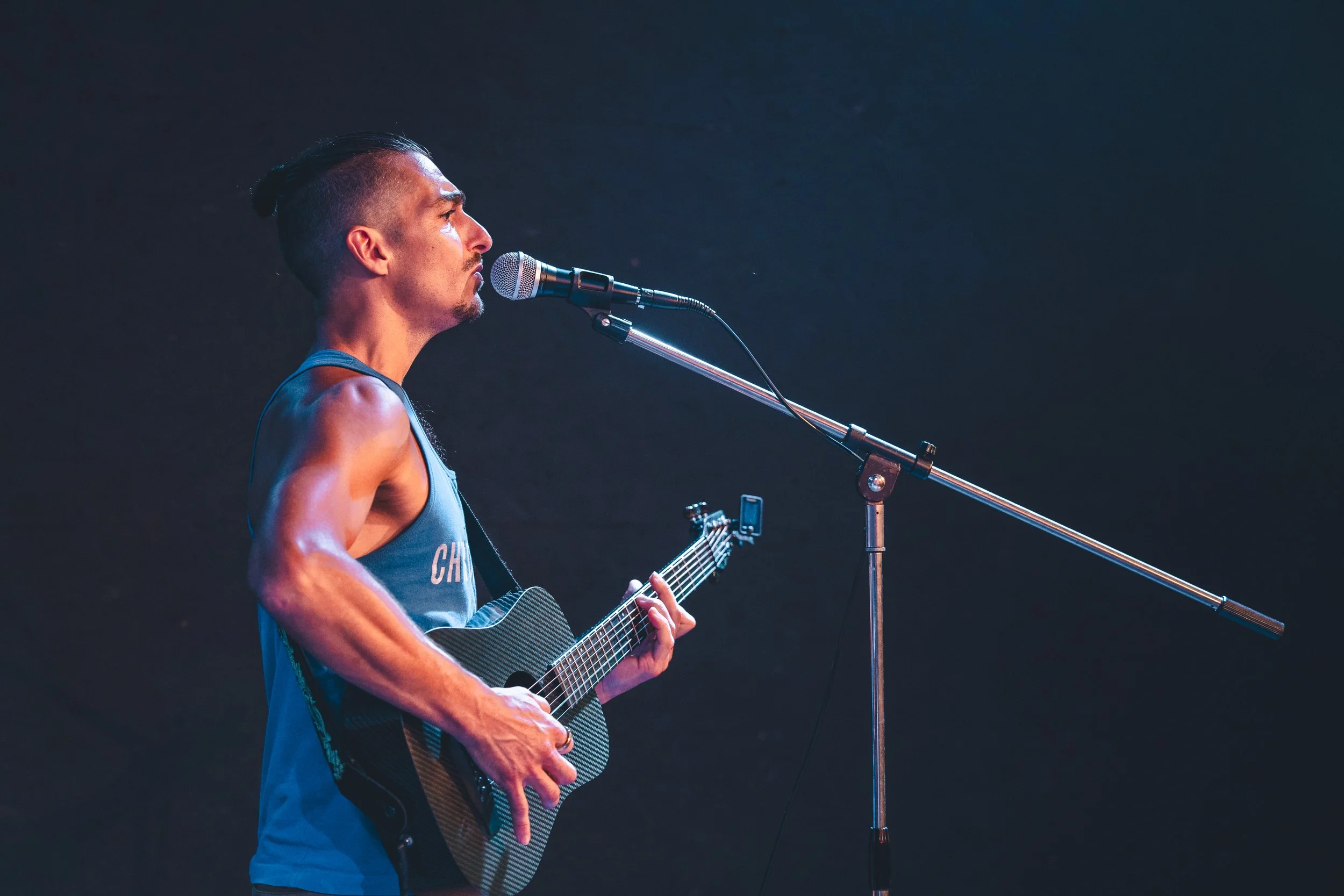 Man singing and playing guitar wearing a blue shirt