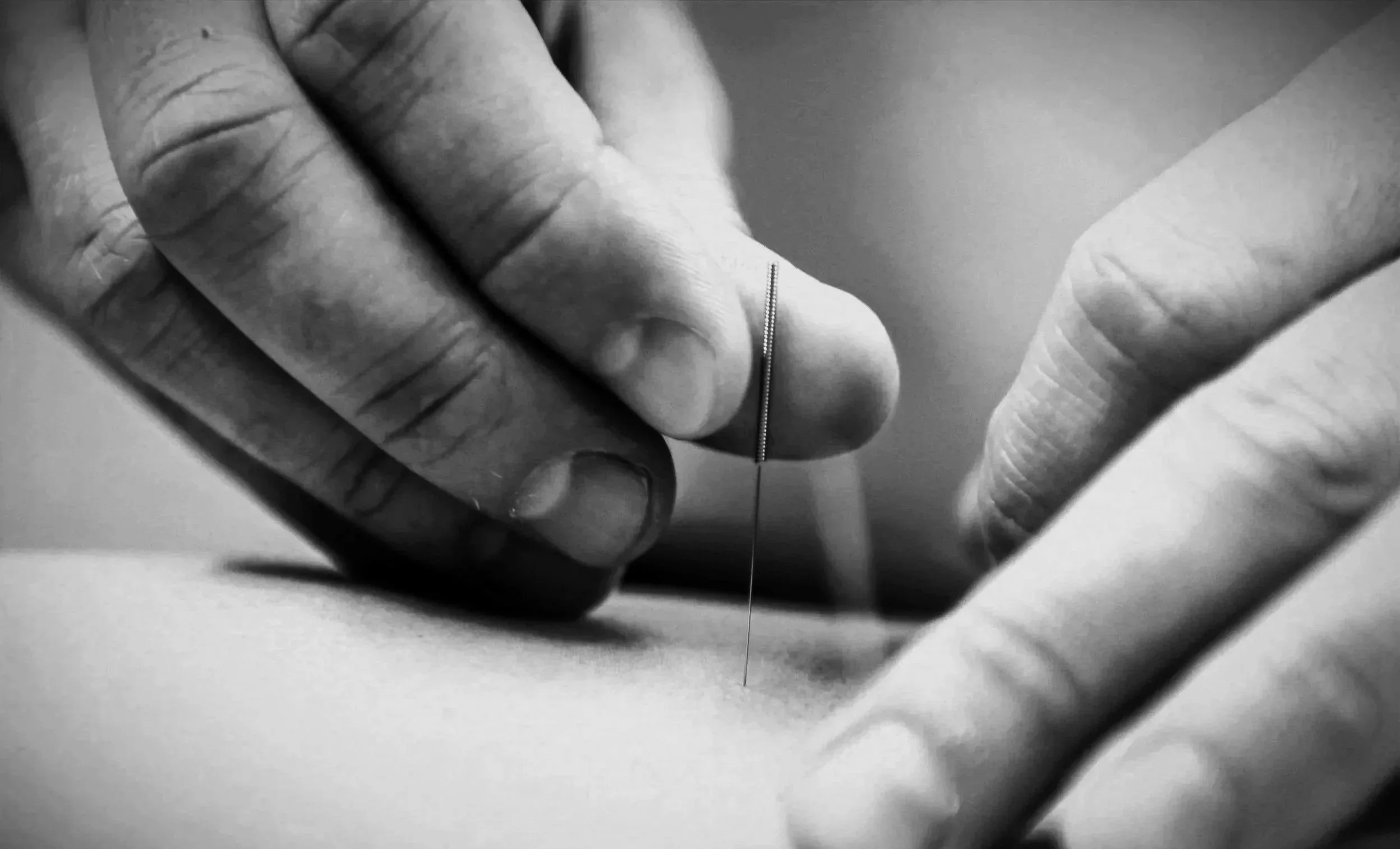 En hand som använder en nål för att sy på en tygbit.