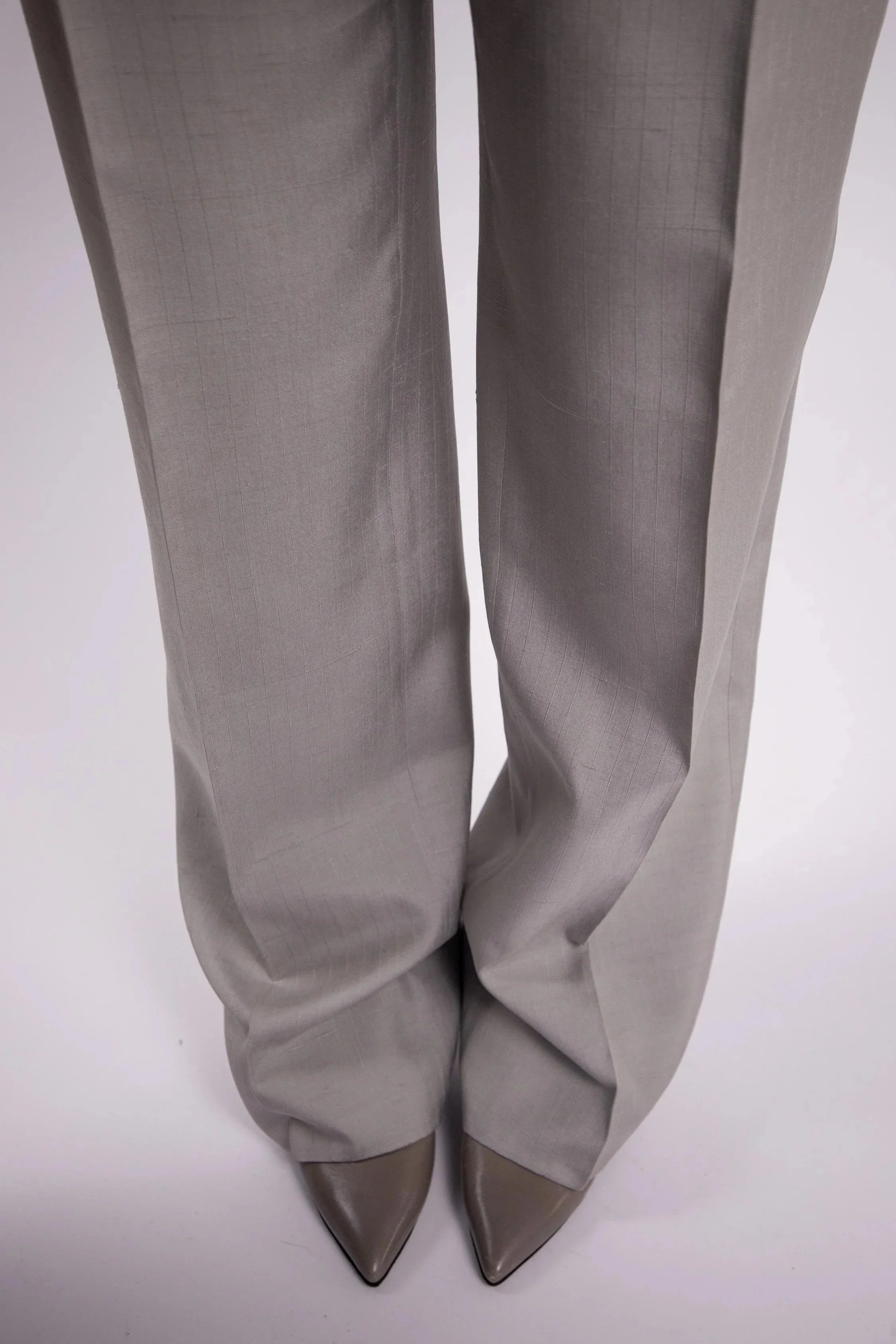 Tailored women’s trousers in light grey wool with precise leg construction and clean finish.