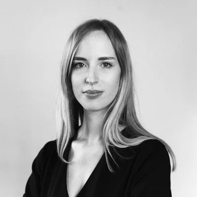 Portrait en noir et blanc d'une femme avec des cheveux longs et lisses, portant une tenue sombre.