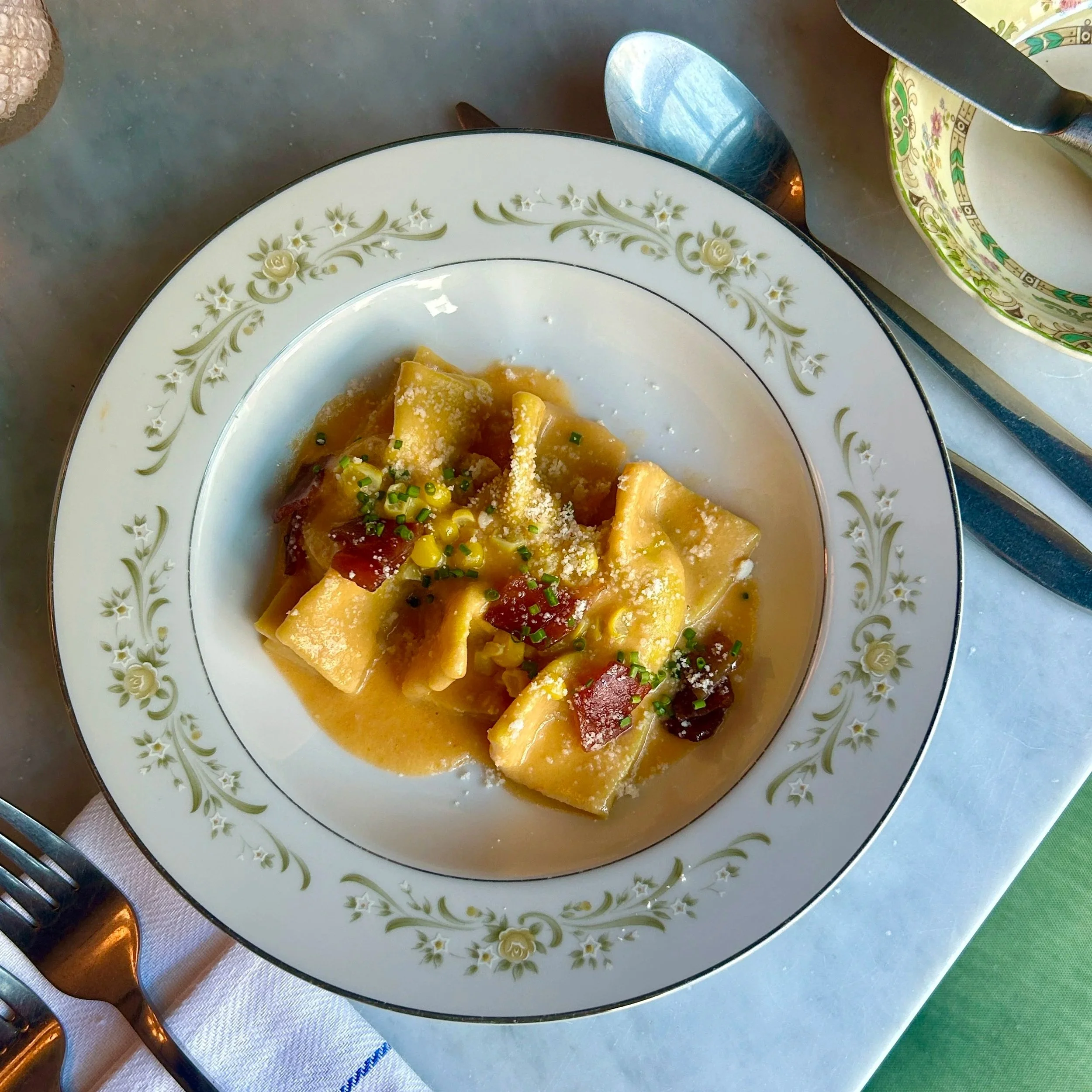 Plate of pasta with sauce, garnished with chopped chives and grated cheese.