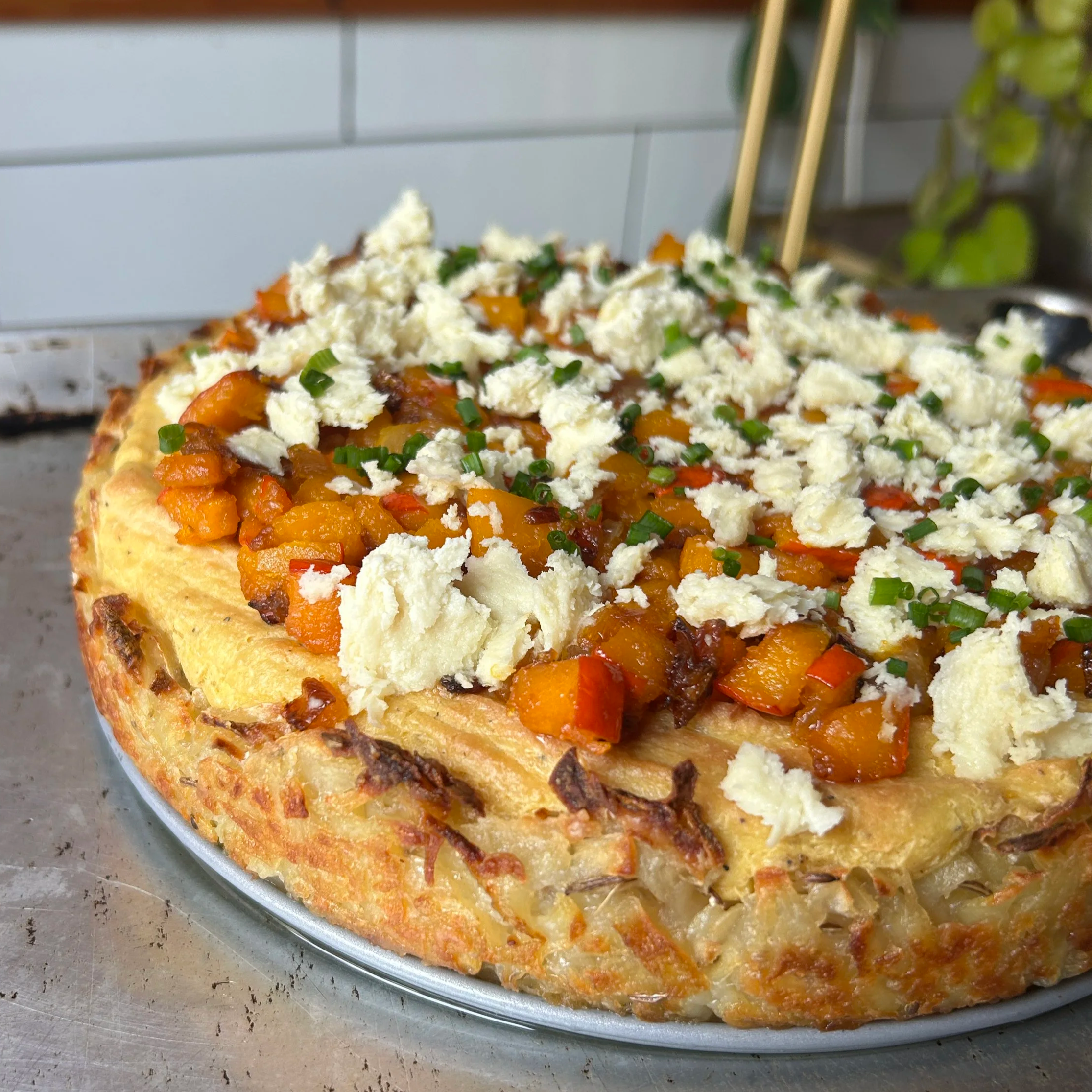 Vegetable casserole topped with crumbled cheese and chopped chives