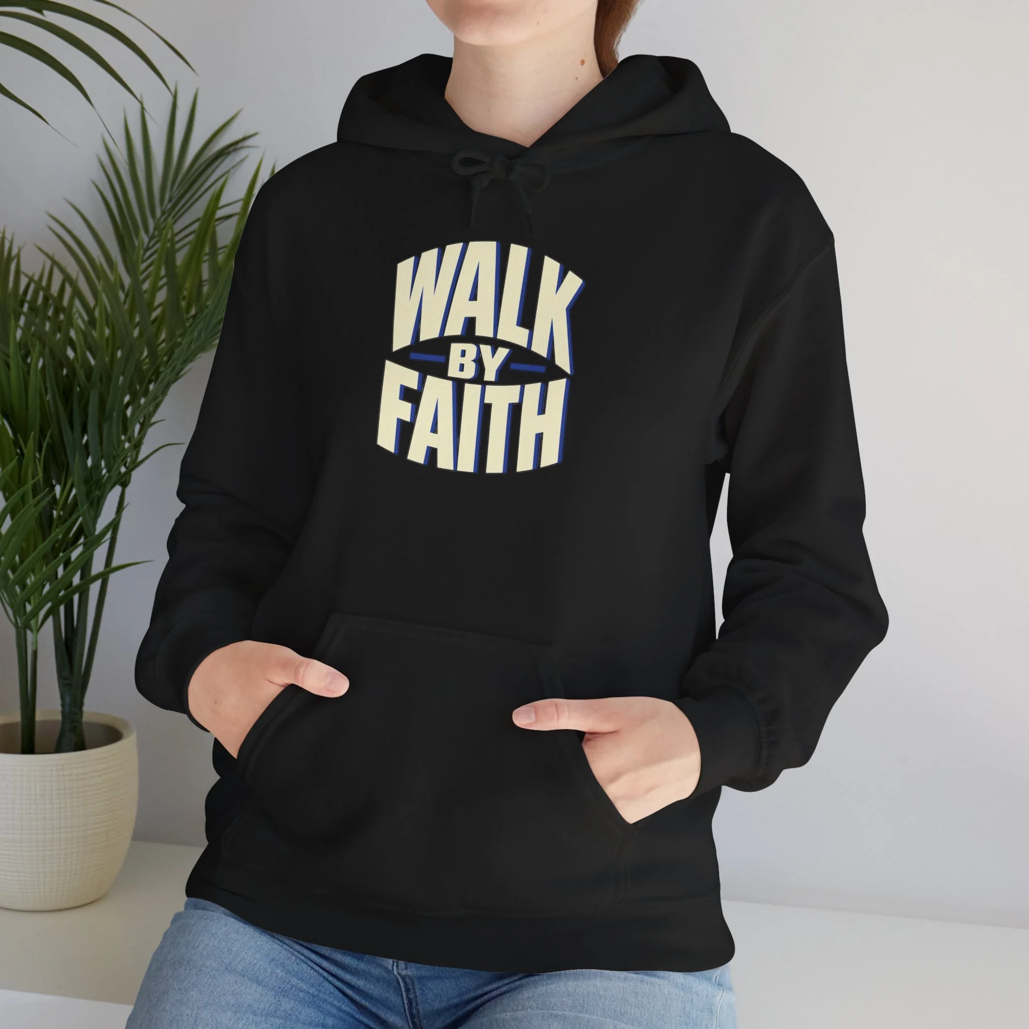 Person wearing the Black Walk by Faith hoodie, close front view of the ivory and cobalt lettering.