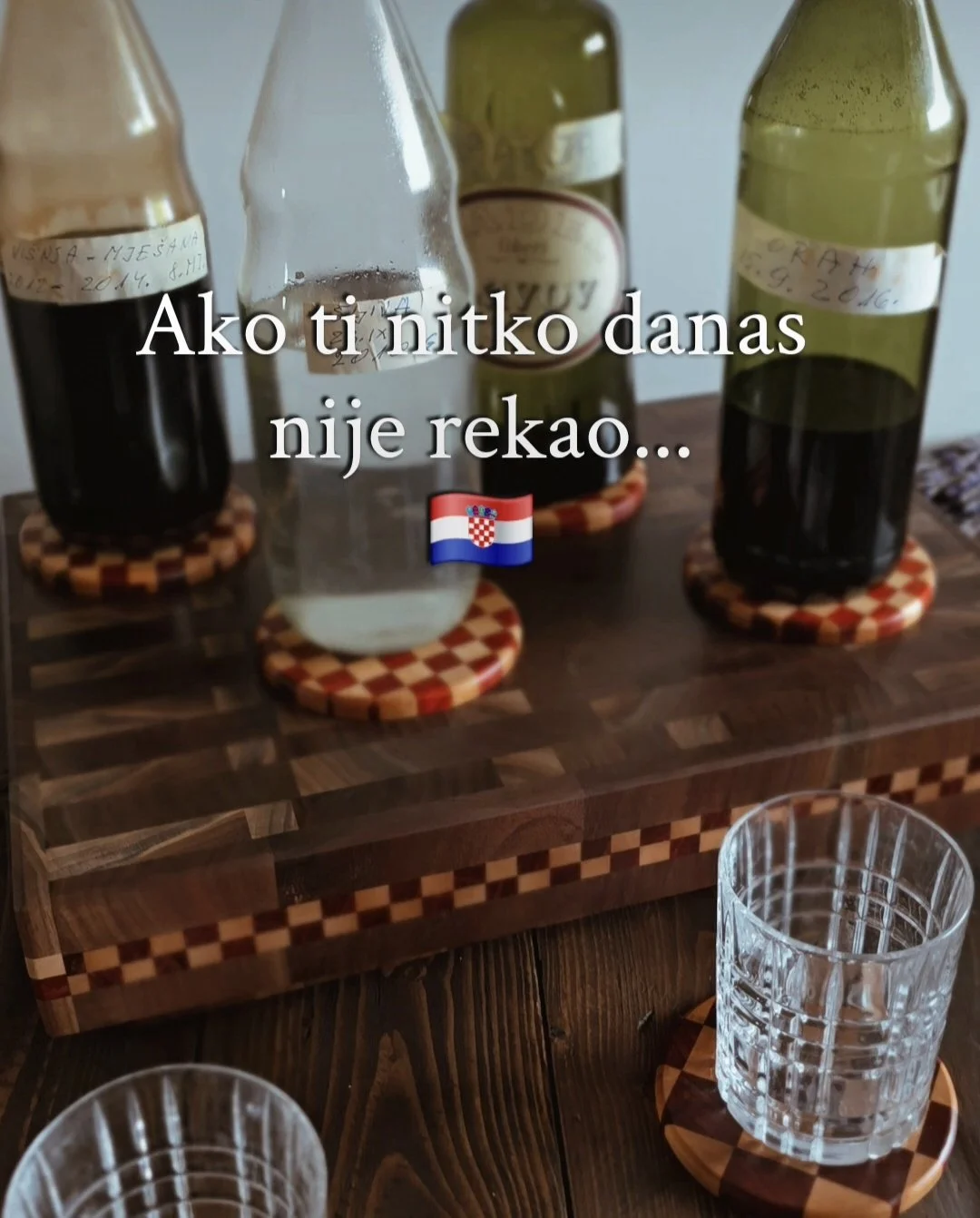 bottles of dark liquid atop coasters on cutting board.