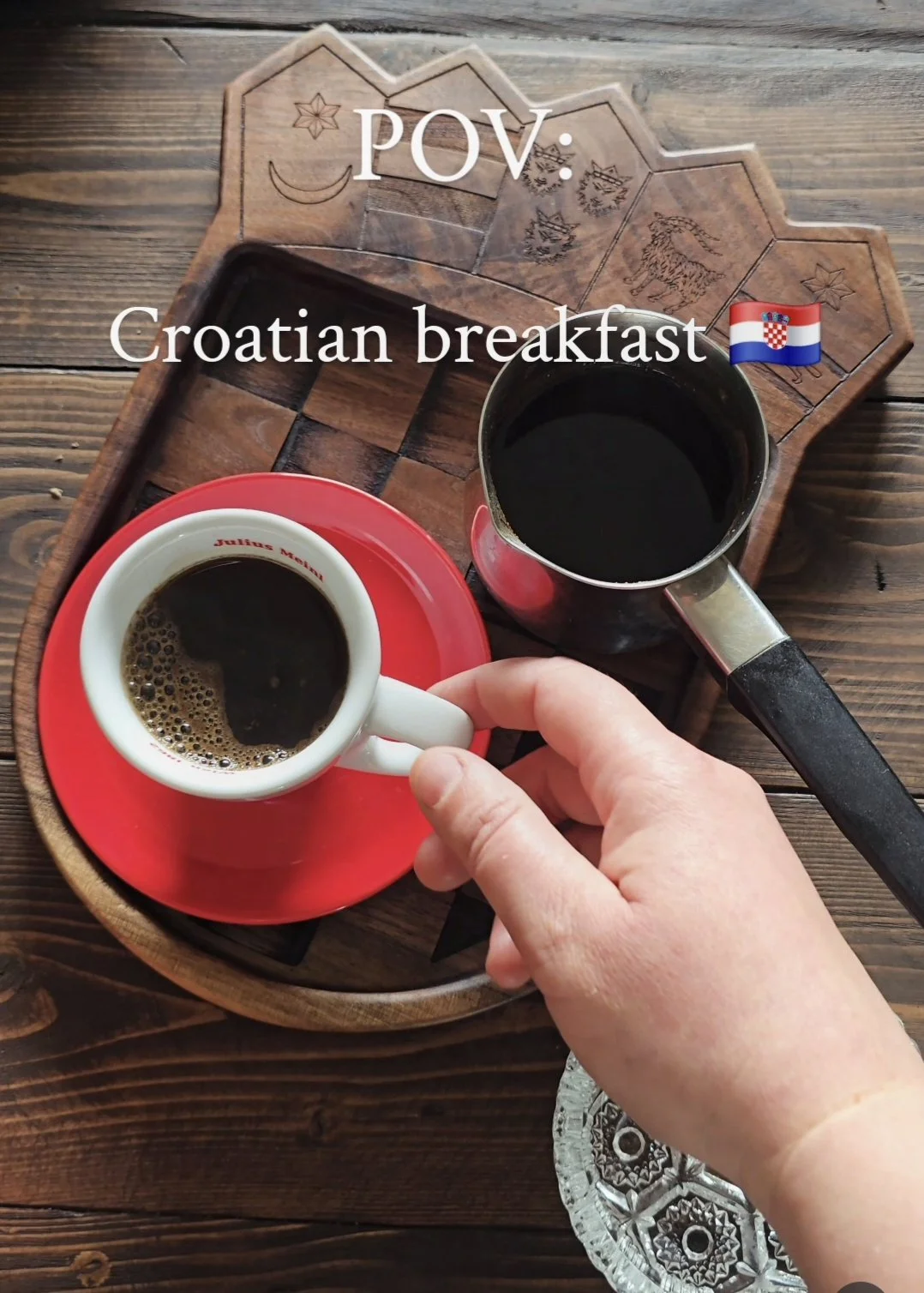 coffee cup and small coffee pot on tray shaped as croatian coat of arms. hand holding coffee
