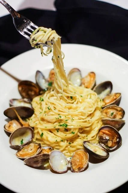 A plate of spaghetti with clams, garnished with parsley.
