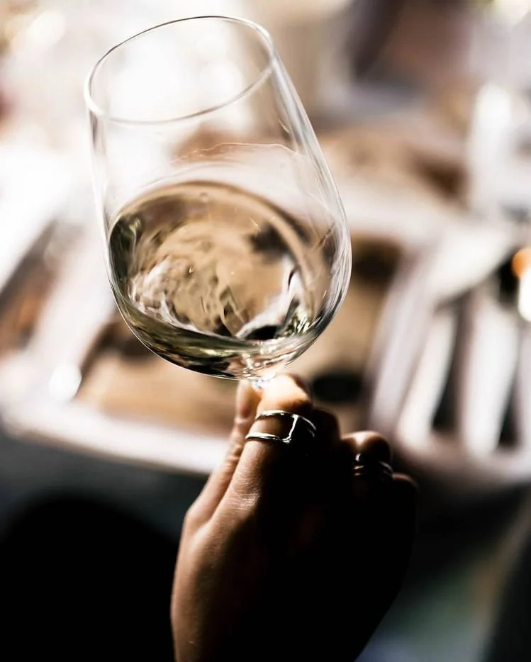 Person holding a wine glass filled with white wine.