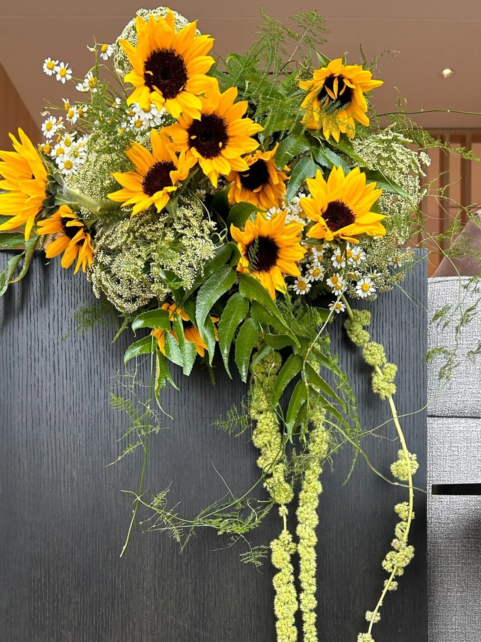 A bouquet of sunflowers with yellow petals and dark centers, mixed with white daisies and greenery, arranged in a bouquet.