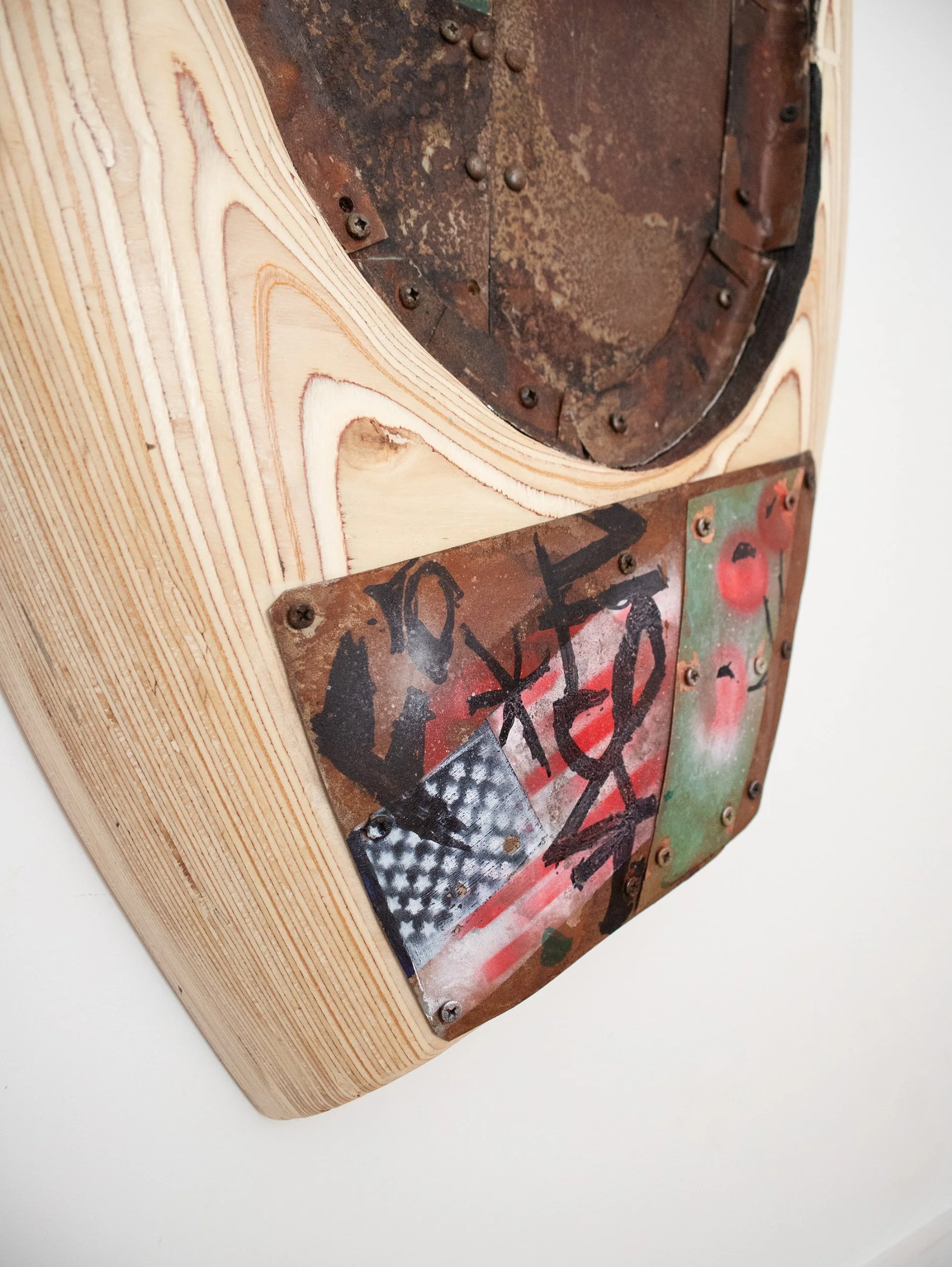 Close-up of the back of a vintage speaker with metal and rusty components mounted on a wooden surface with visible wood grain.