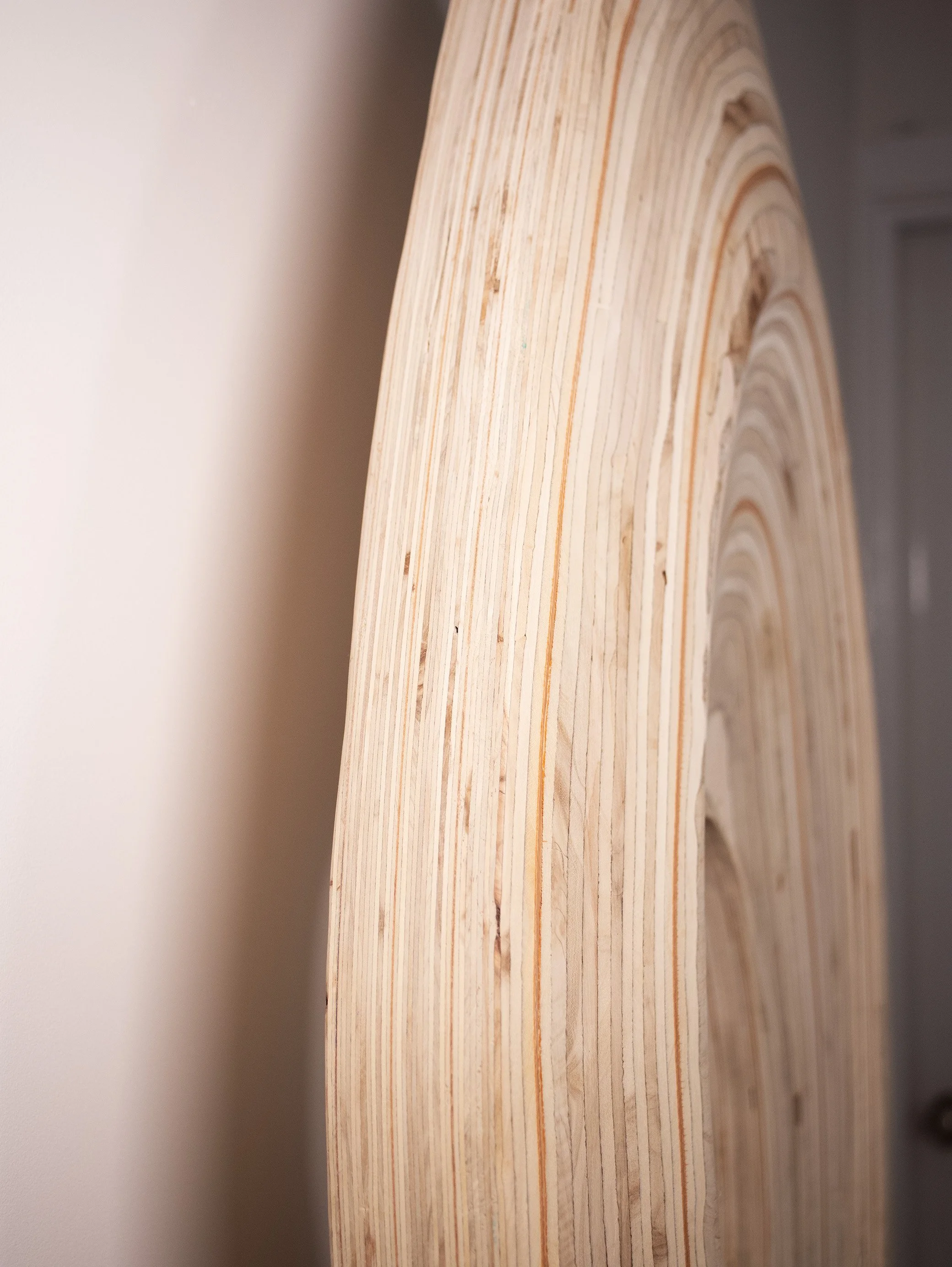 Close-up of a wooden object with visible grain and ring patterns, likely a piece of lumber or plywood.