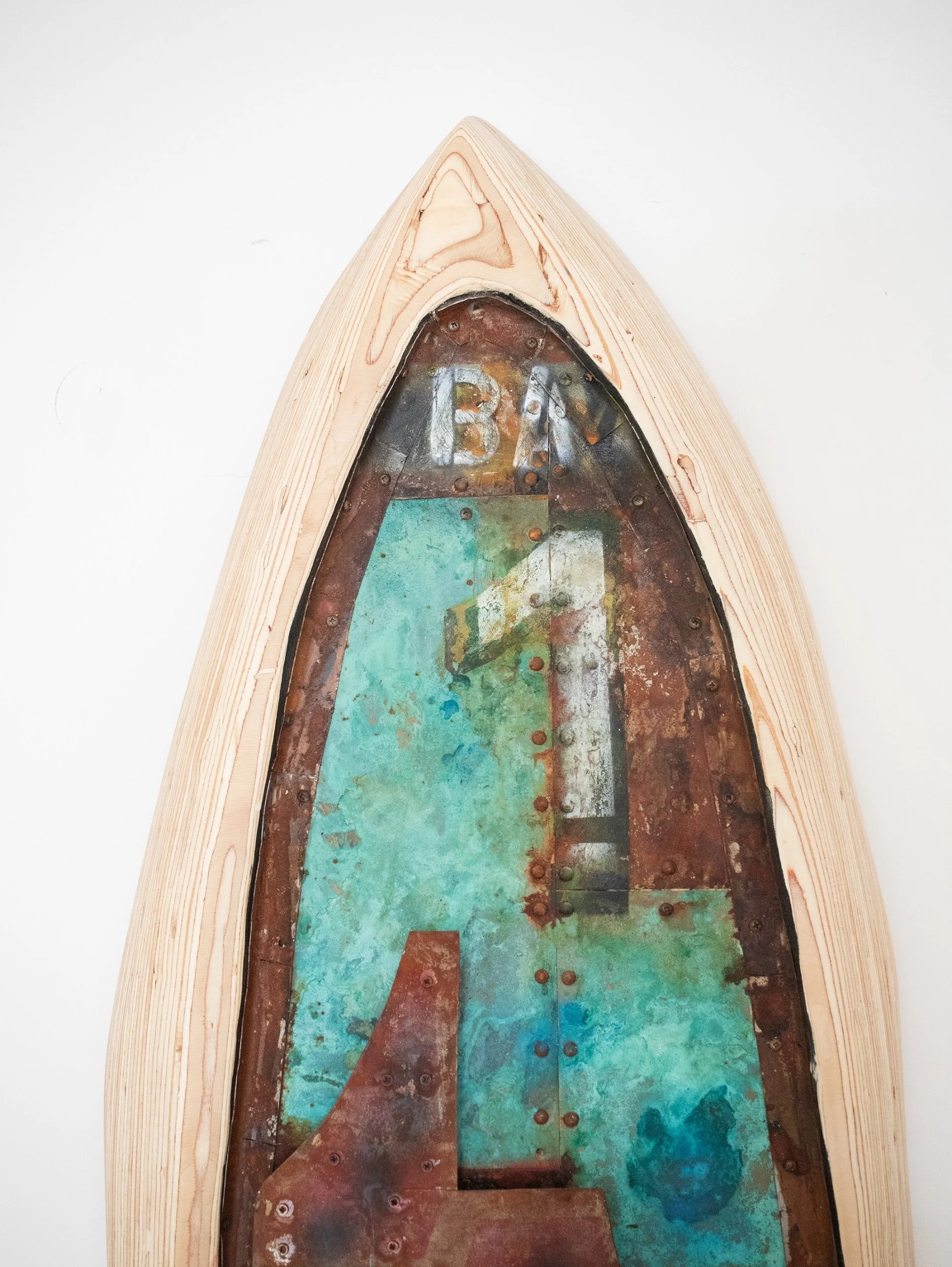 Close-up of the inside of a wooden boat hull with a painted metal bottom, showing rust, patina, and rivets.