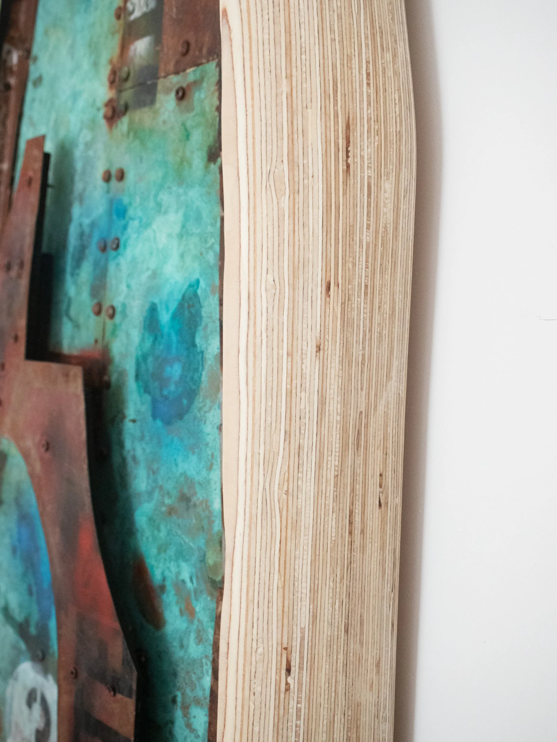 Close-up of a stack of light-colored wooden planks and an adjacent painted surface with blue and green hues.