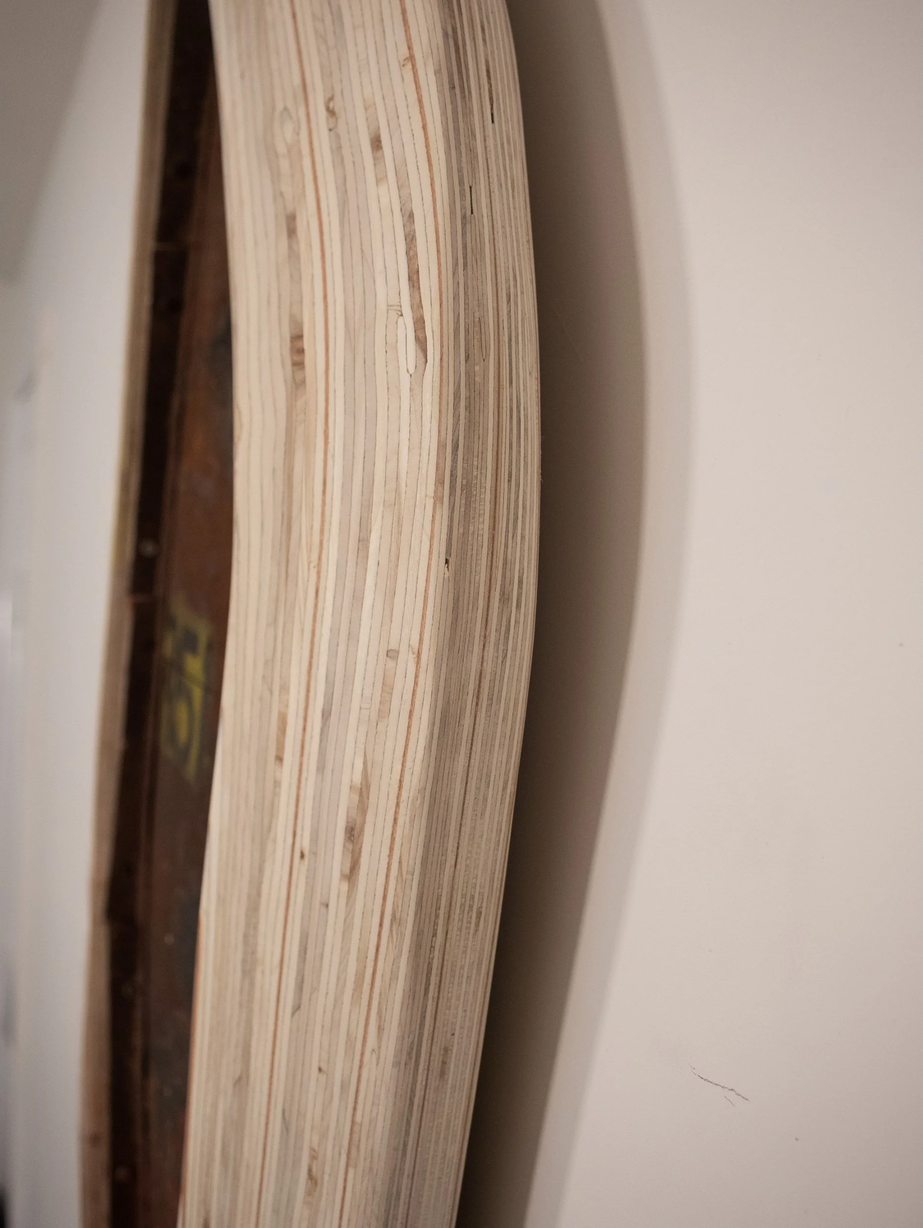 Close-up view of stacked wooden planks or boards leaning against a white wall.