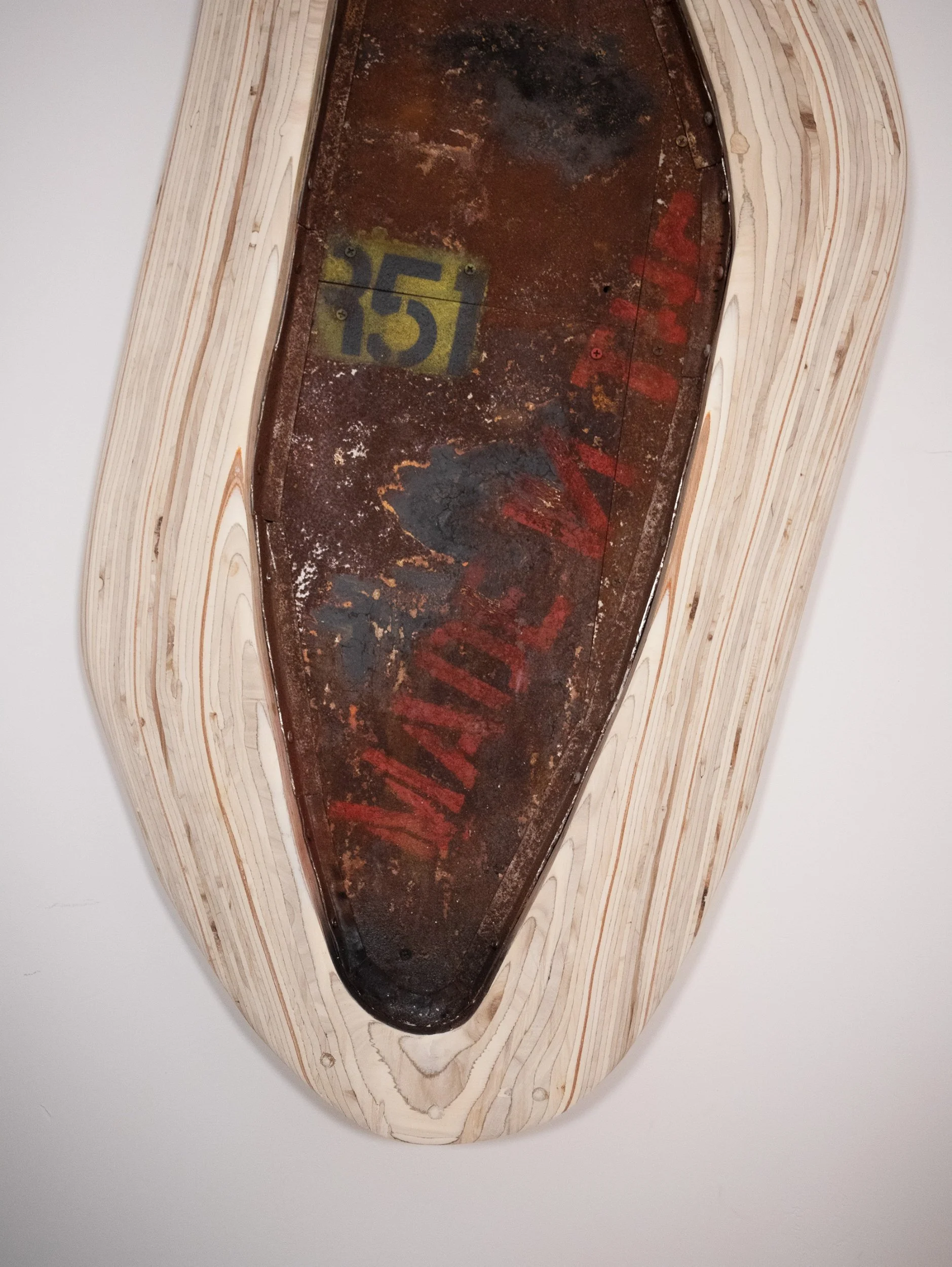 Vintage baseball glove with a dark brown leather pocket and red writing, mounted on a light wooden display with visible wood grain.