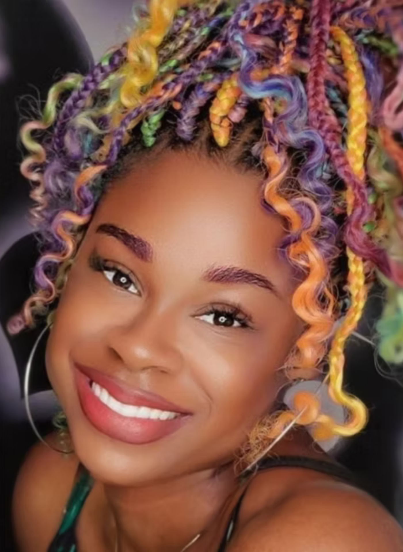 Close-up of a woman with multicolored, curly braids smiling.