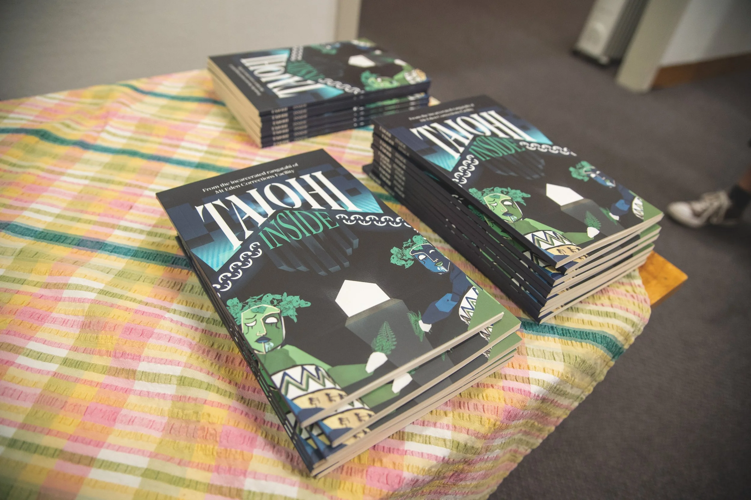 Stack of books titled 'Holly Inside' on a colorful checkered cloth table.