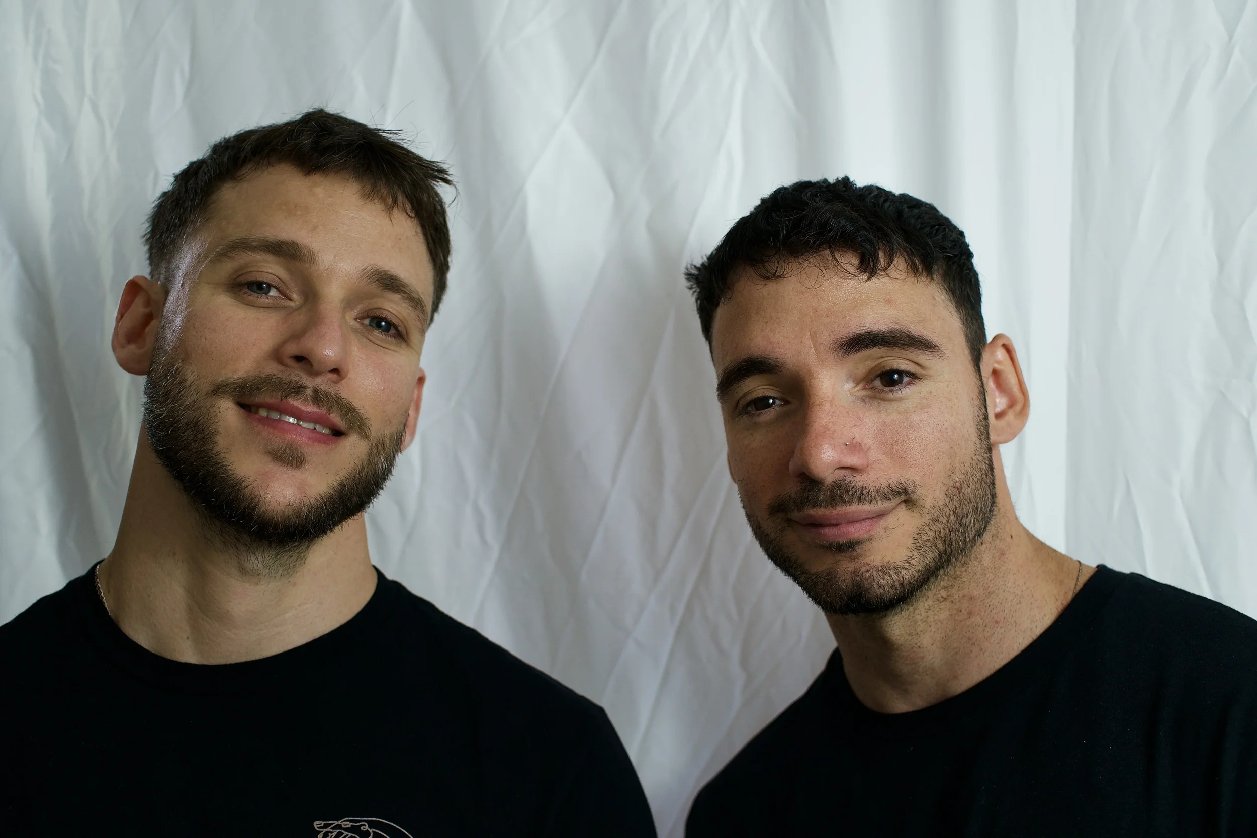 Two young men Roger & Bayan smiling for a photo against a white backdrop.