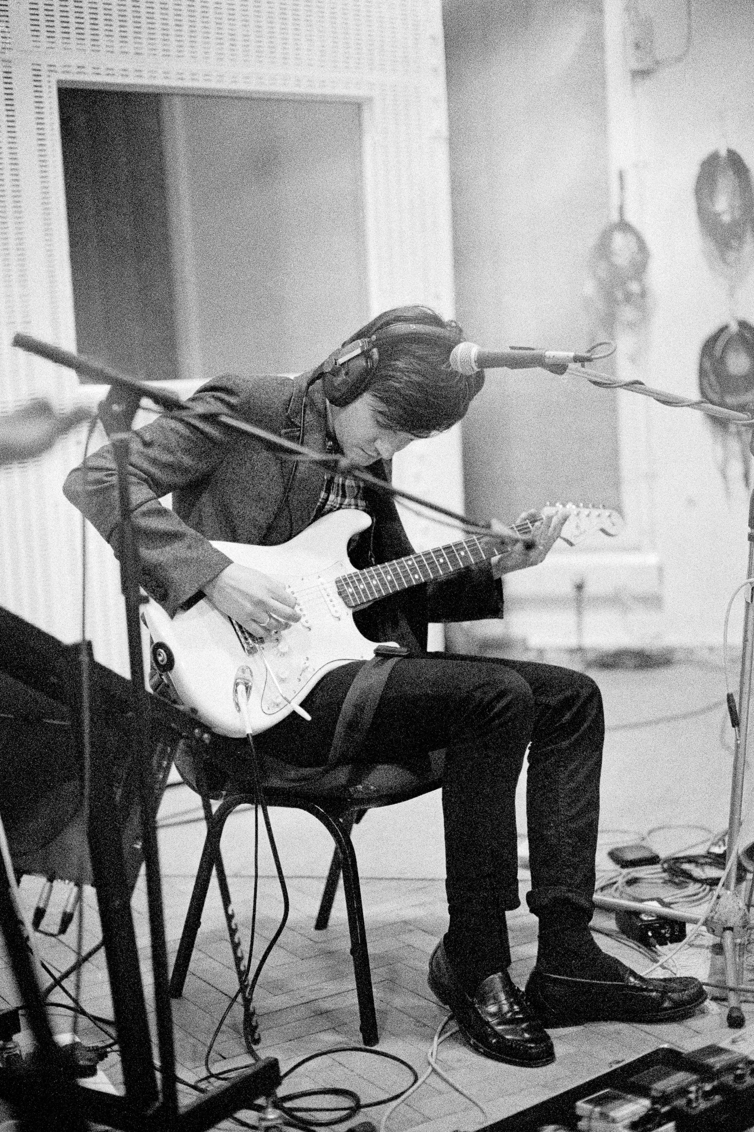 Musician in a recording studio playing an electric guitar.