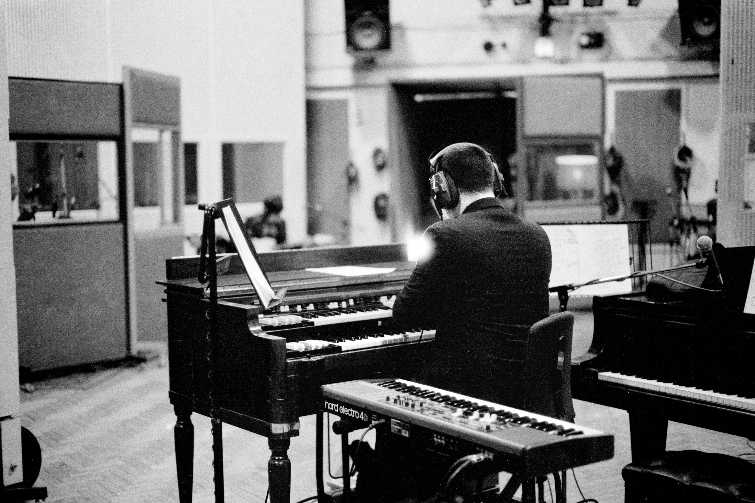 A man wearing headphones playing a piano in a recording studio.