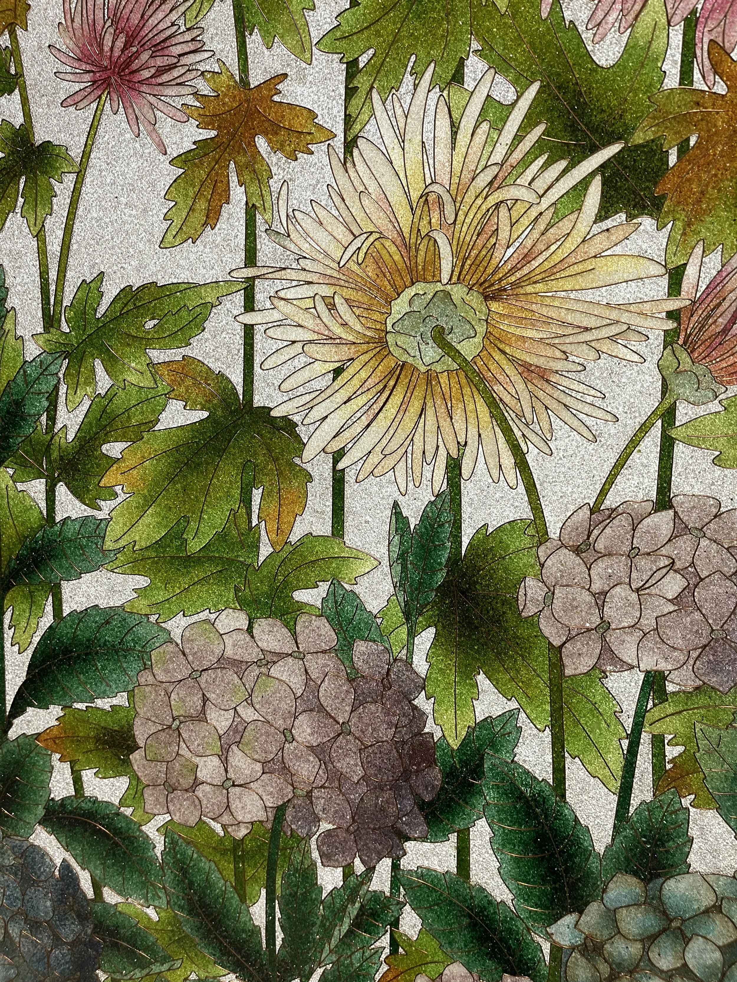 Close-up view of a mosaic artwork featuring flowers and leaves with intricate details and vibrant colors.